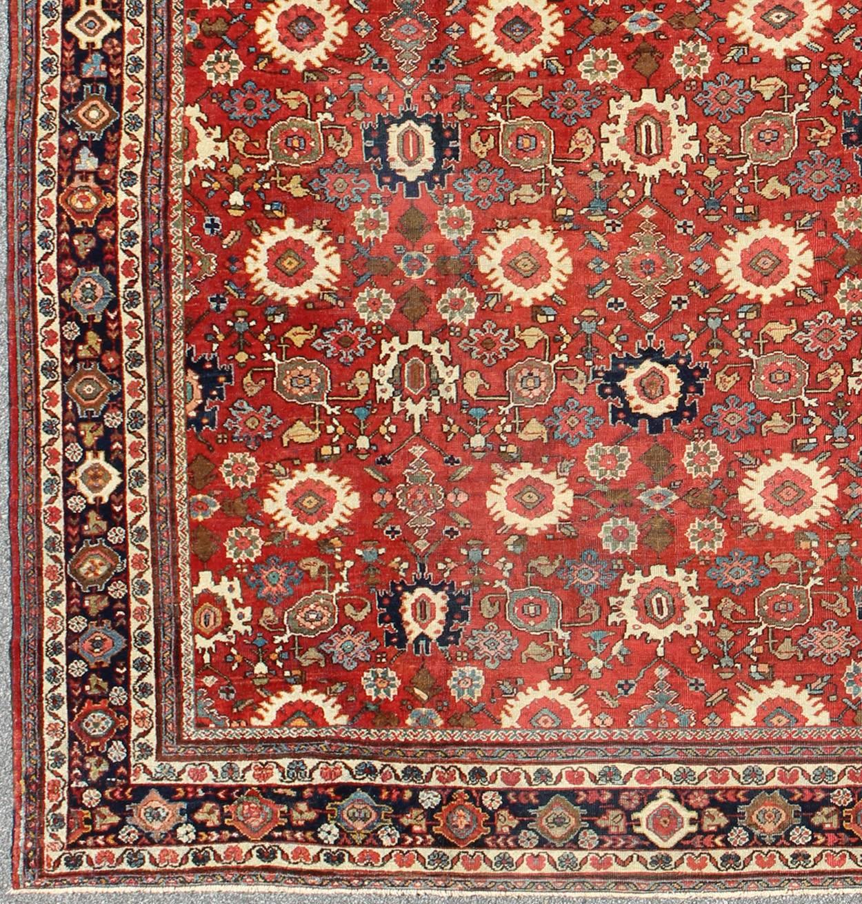 This beautiful antique Large Persian Mahal features an all-over sub-geometric pattern of star bursts, leaves, flower blossoms and palmettes. Colors include red, blue, ivory, and black.
Measures: 11'5 x 14'5.