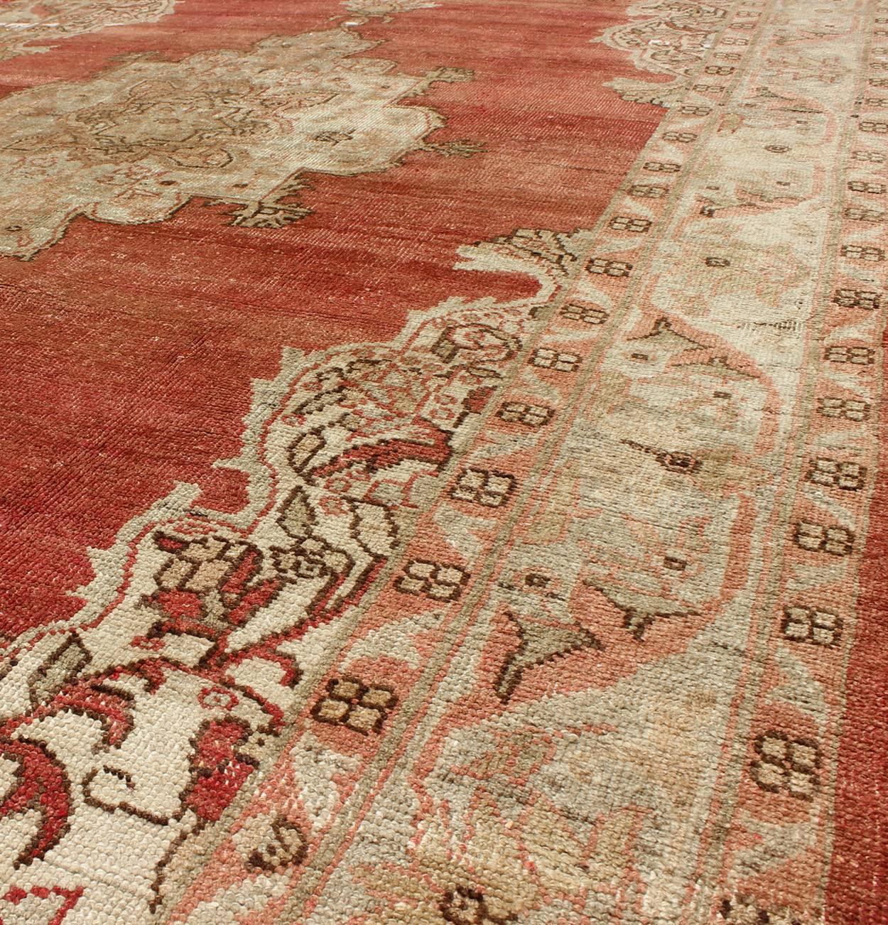 Milieu du XXe siècle Ancien tapis turc d'Oushak à médaillon avec fond rouge doux, taupe et vert pâle en vente