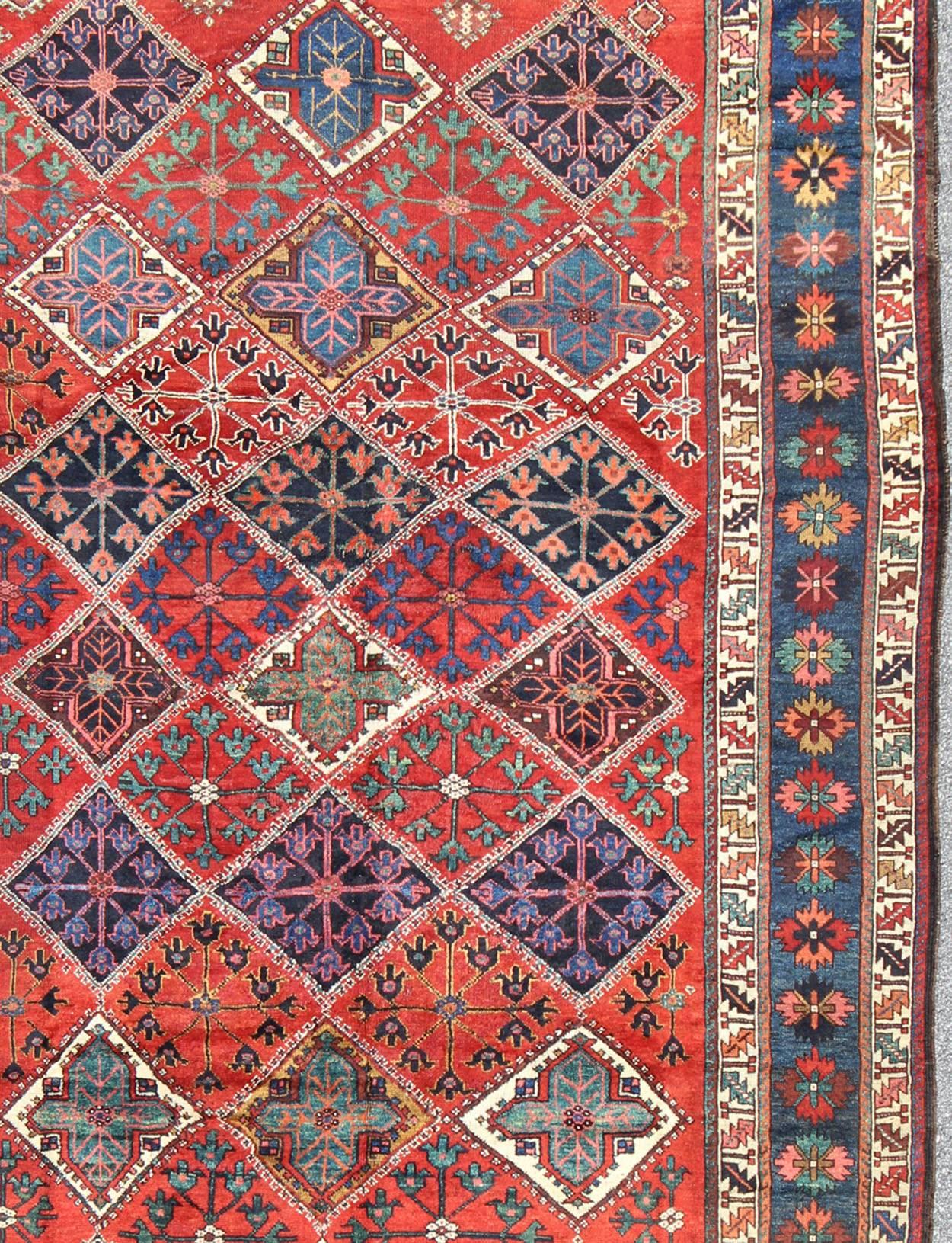 This amazing antique Persian Qashqai rug originates from the tribes of southwestern Iran and features a wonderful geometric pattern and traditional color palette. The variations of red, blue and ivory beautifully form the field and various