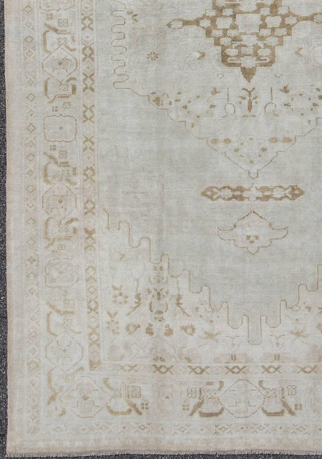 Measures: 7'3'' x 11'2''.
This vintage Oushak carpet beautifully integrates neutral color compositions to decorate a calm and serene room with a subtle geometric medallion pattern rendered in a faded gold, brining more life to the piece.  This rug