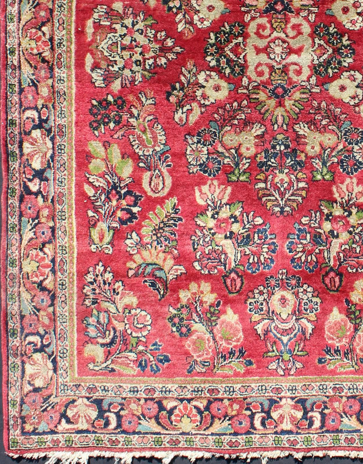 This piece is a wonderful, early 20th century Persian sarouk rug. A masterfully woven beautiful Red field of large tree branches and a myriad of floral varieties are woven in dark and light red, crimson and cream naturally dyed. The wide border