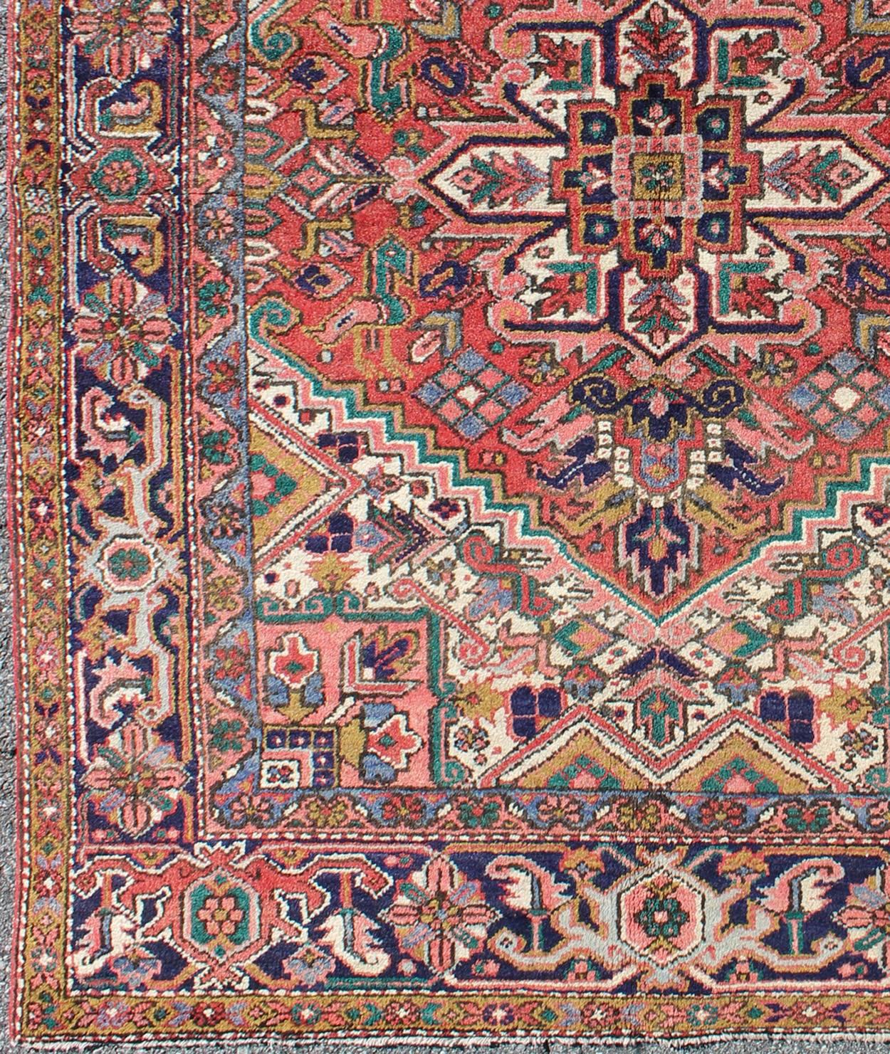 This vintage Persian Heriz rug features a jewel-toned geometric design and center medallion. 
Measures: 4.10 x 6.6.