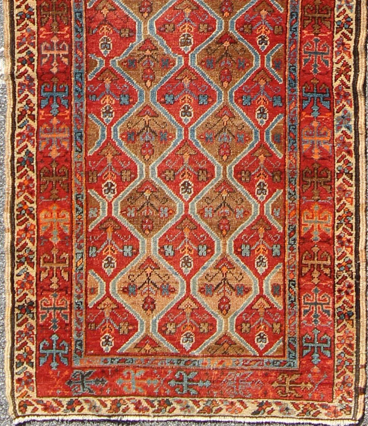 Measures: 2'10'' x 10'9''.
This antique Serapi-Heriz displays a charming and rich combination of various jewel tones. The geometric diamond shapes are repeated in different forms and colors throughout the background while the border repeats a motif