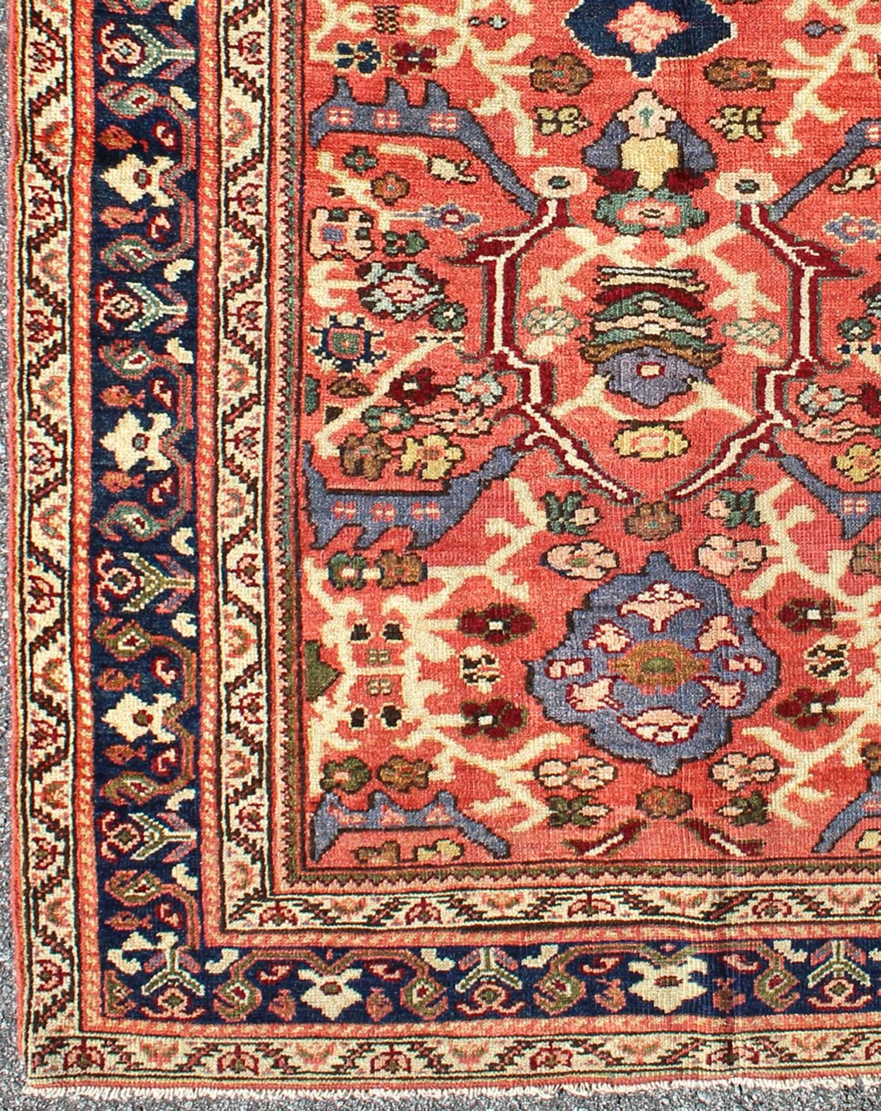 A beautiful Sultanabad rug, this piece features a cinnamon-shaded field bearing an intricate floral motif of repeating red, light purple and pink flowers. A thin blue border displays straight rows of single blossoms, interspersed with ruyi or