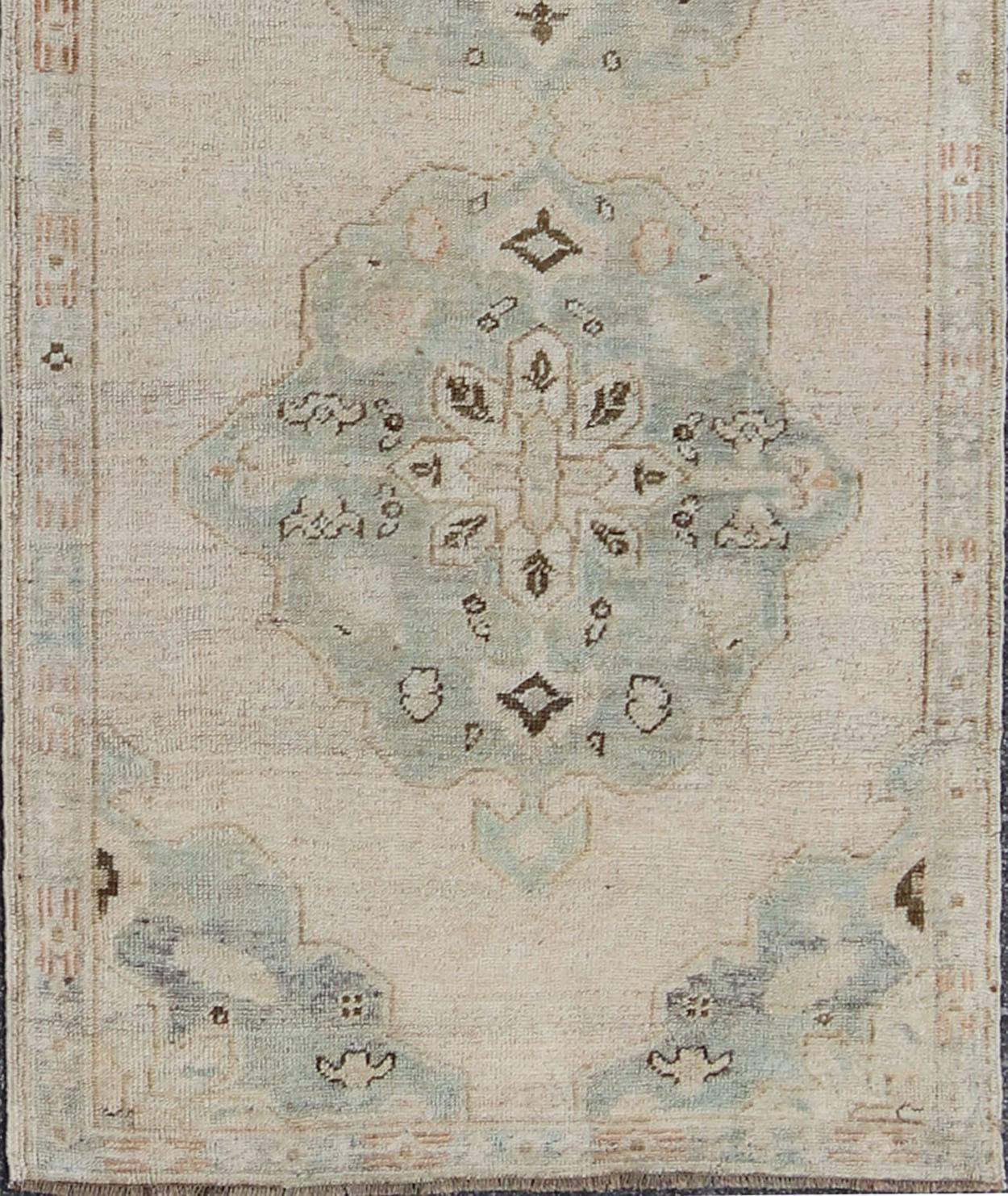 Measures: 3'3 x 9'8.
This beautiful Oushak runner features a Classic Oushak design, which is enhanced by lustrous wool. The faint ivory or champagne ground is home to three elegant sea-foam green/ blue medallions. Four-light blue cornices hold the
