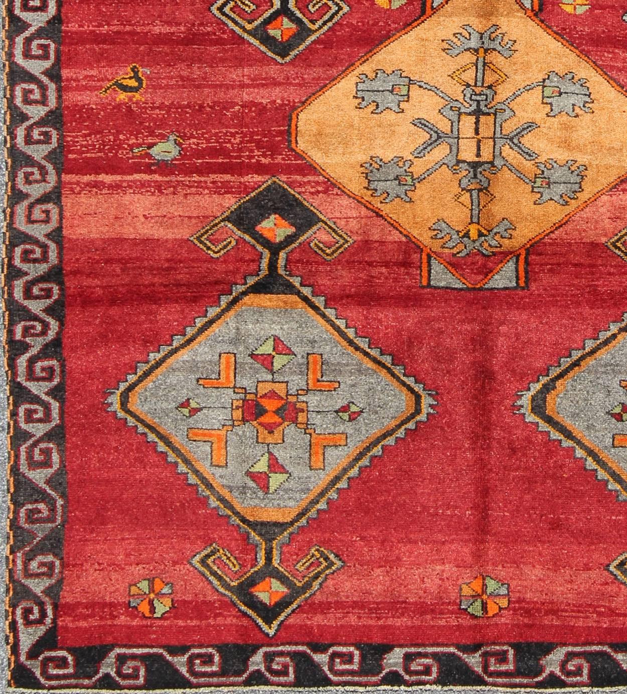 This Kars wool rug, handwoven in Turkey, features exquisite traditional medallions in a bright palette with pops of orange, charcoal and gray. An ornate charcoal border, detailed with a repeating pattern, frames a striated red field. 

Measures: