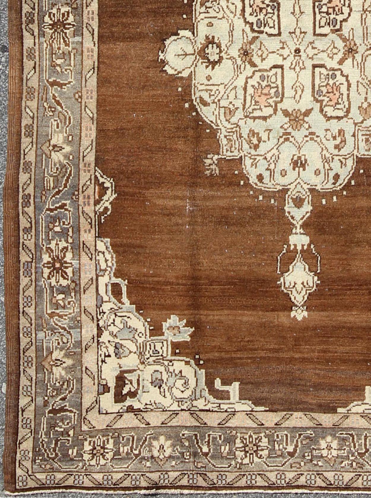 Türkischer Oushak-Teppich mit floralen Motiven in Schokoladenbraun, Elfenbein und Taupe
Dieser wunderschöne Teppich aus der Türkei des frühen 20. Jahrhunderts zeigt ein klassisches Oushak-Muster, das durch die glänzende Wolle noch verstärkt wird.