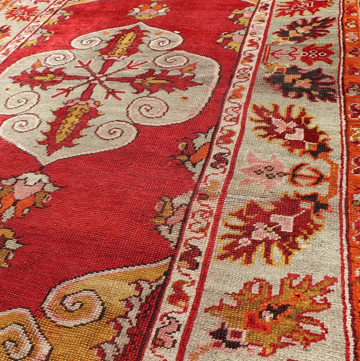 Early 20th Century Center Medallion Antique Turkish Oushak Rug with Red Ground & Multi Colors For Sale