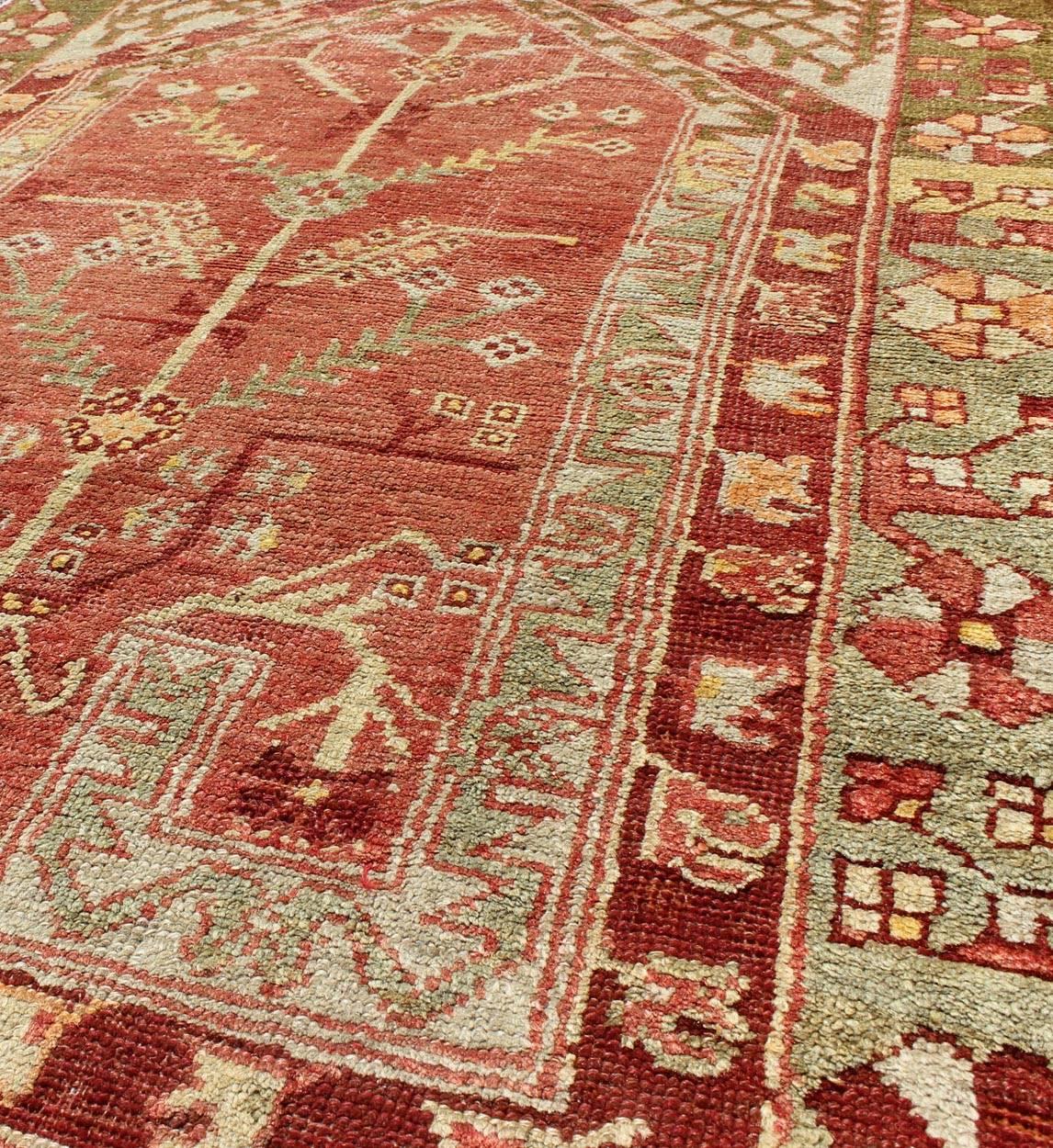 Antique Oushak Rug with Directional Tribal Motifs in Soft Pink Red & Green In Excellent Condition For Sale In Atlanta, GA