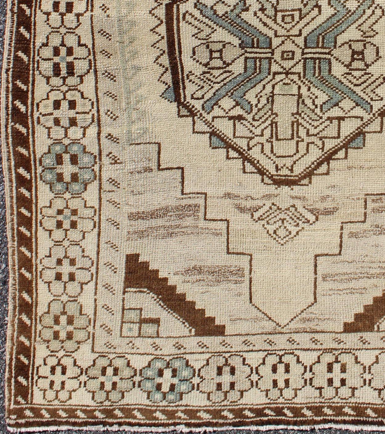 This vintage Oushak rug features an intricately beautiful design. The central medallion is complemented by a gorgeous symmetrical set of stylized geometric-tribal motifs. The various shades of cream, brown, and light blue.

Measures: 3'3'' x