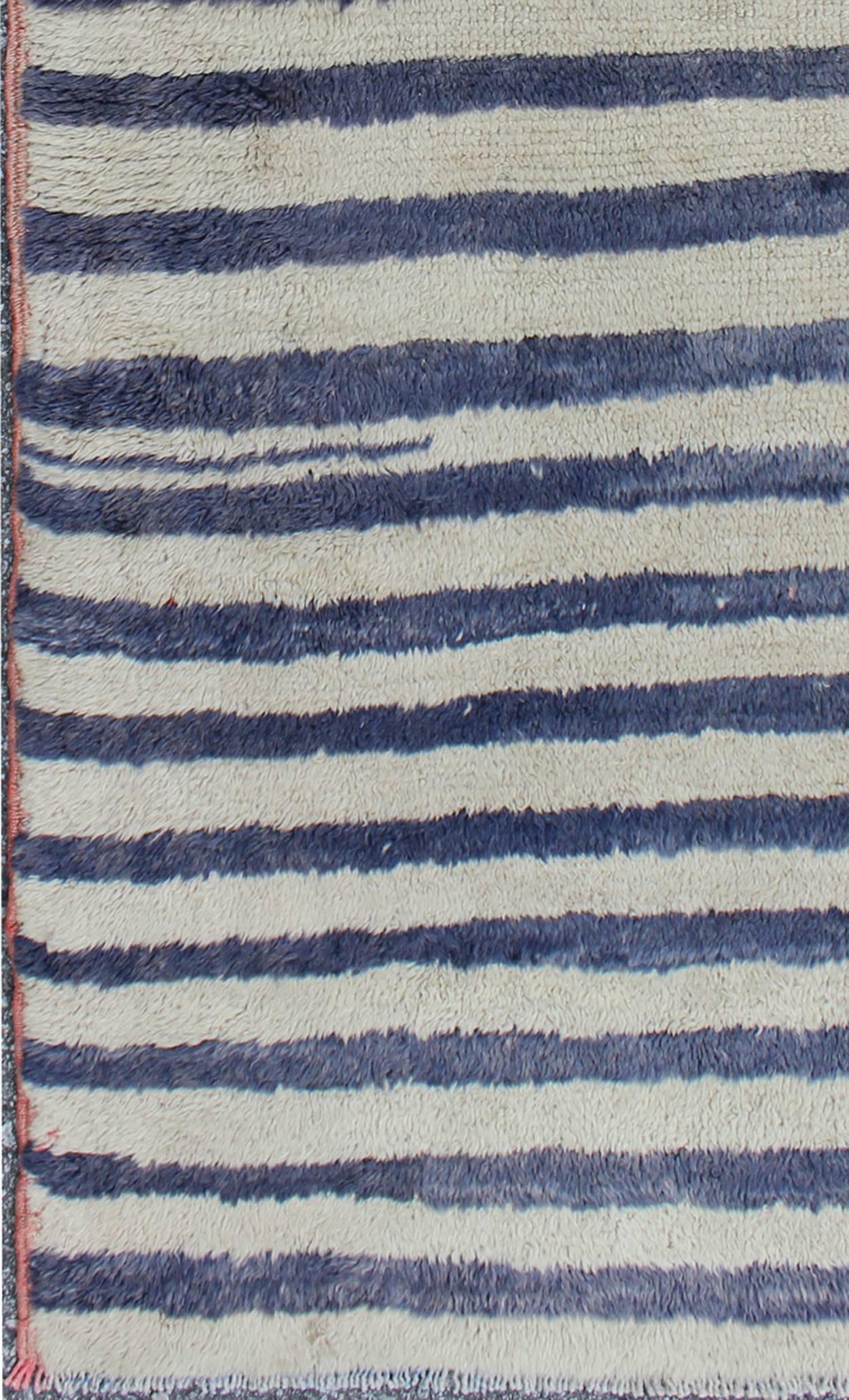  Tulu Carpet with Cream and Navy Blue Stripe Pattern rug/en-141520  origin/turkey 

This high-pile shaggy Tulu rug is handwoven from wool in a soft color palette, featuring a striped pattern of cream and navy blue. Tulu carpets' unique texture and