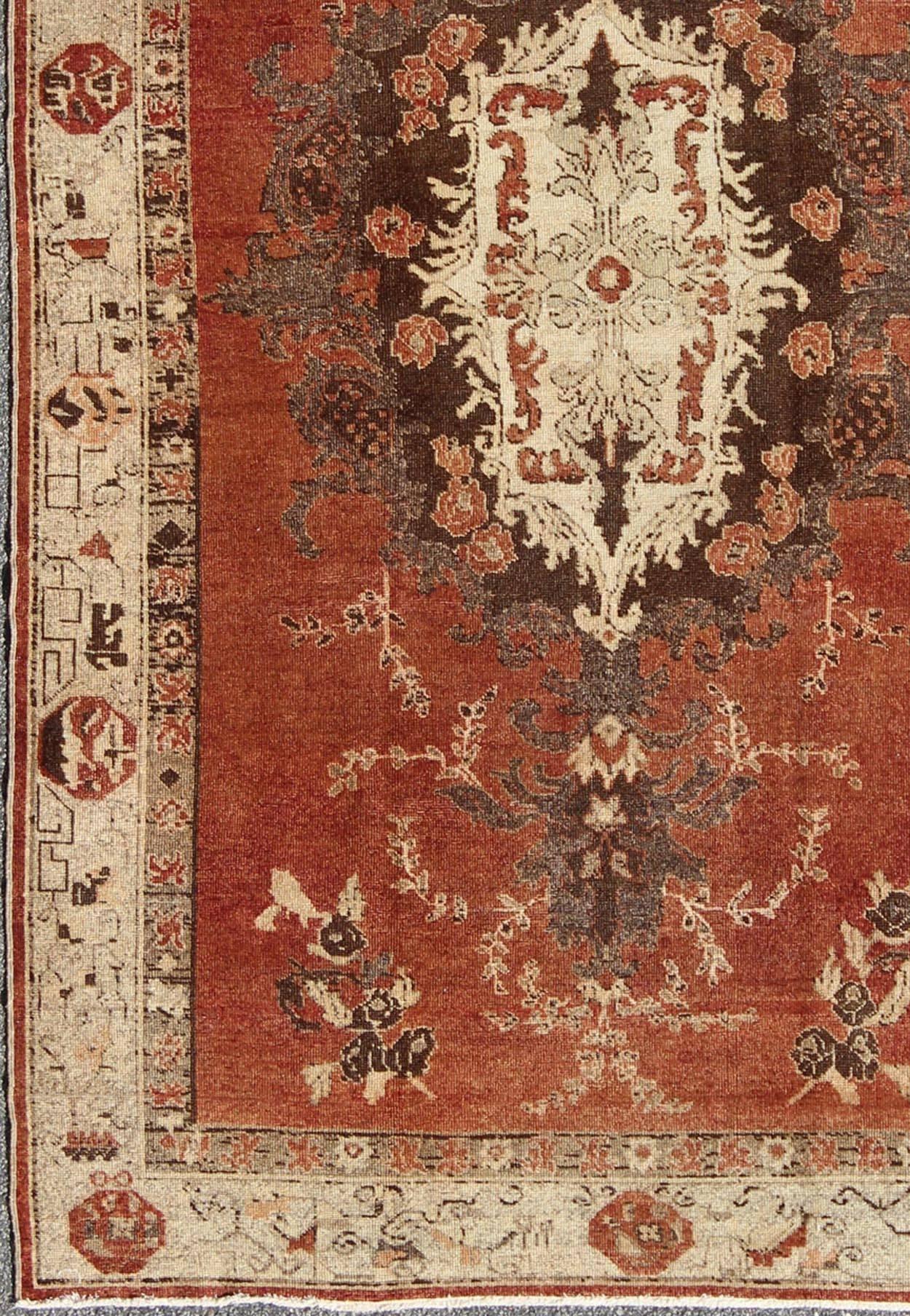 Vintage Oushak Carpet from Turkey with Faint Red Field and Floral Medallion. This vintage Turkish Oushak rug features a unique blend of colors and an intricately beautiful design. The central medallion is complemented by a symmetrical set of floral