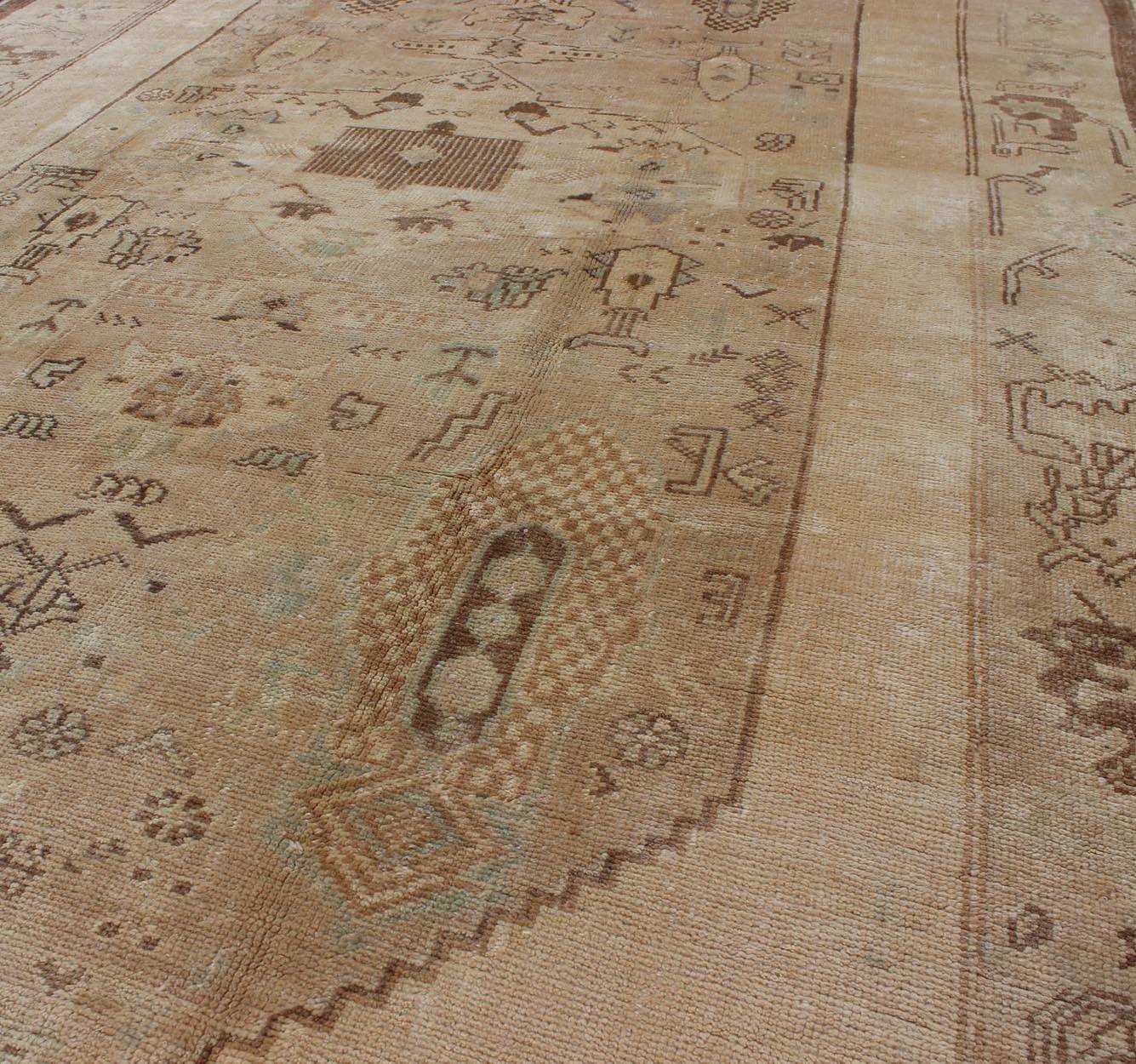 Türkischer Oushak-Teppich im Vintage-Stil mit Stammesfiguren in einer erdigen Farbpalette, Vintage (20. Jahrhundert) im Angebot