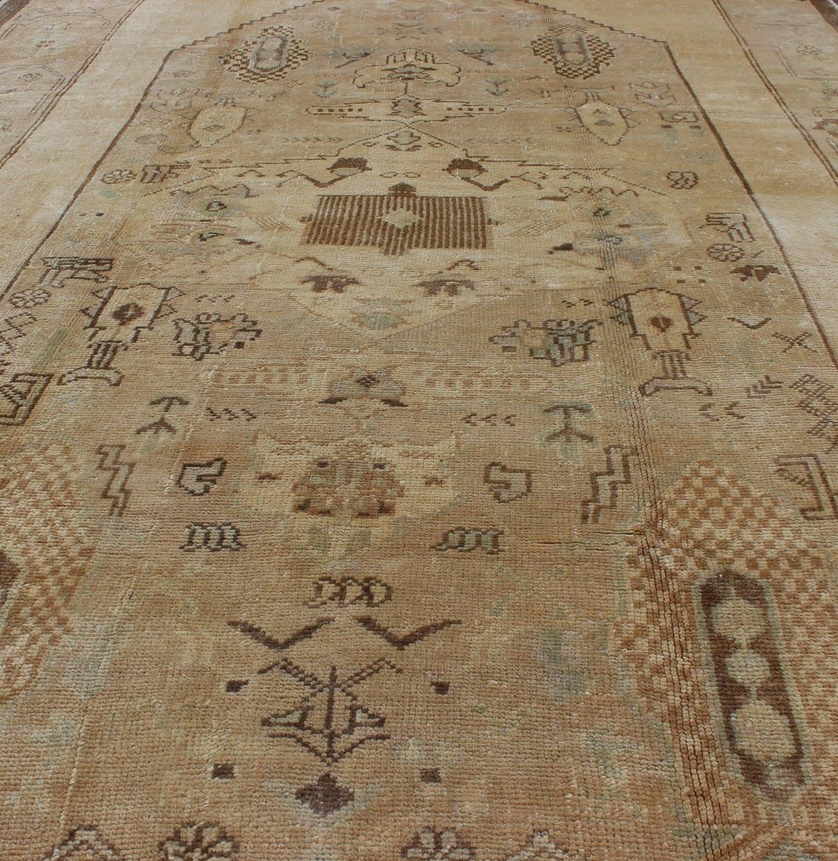 Türkischer Oushak-Teppich im Vintage-Stil mit Stammesfiguren in einer erdigen Farbpalette, Vintage (Wolle) im Angebot