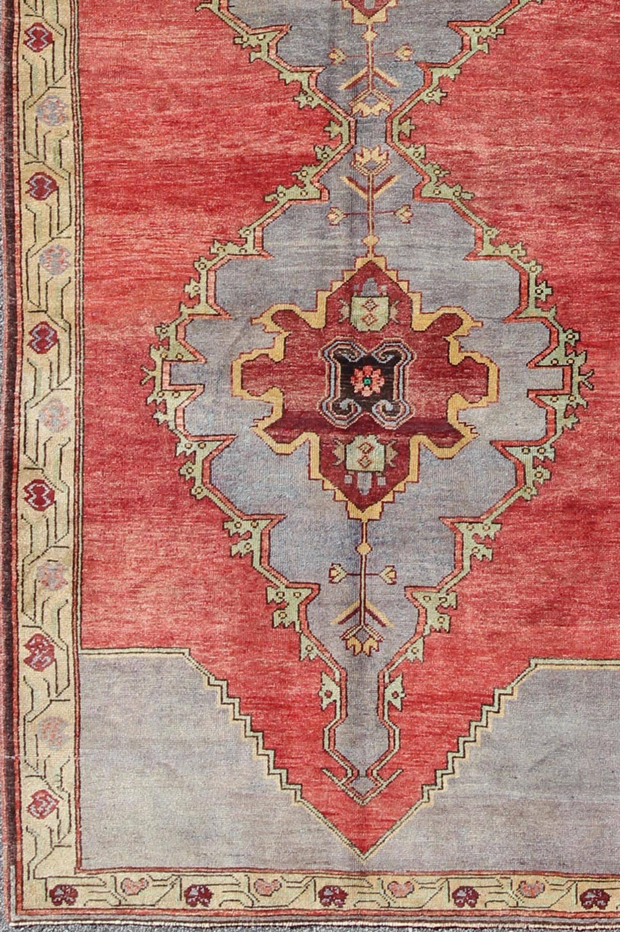 This beautiful vintage Oushak runner from mid-20th Century Turkey features a Classic Oushak design, which is enhanced by its lustrous wool. The red ground is home to three large and elegant medallions of gray, red, green, and yellow tones. Vining