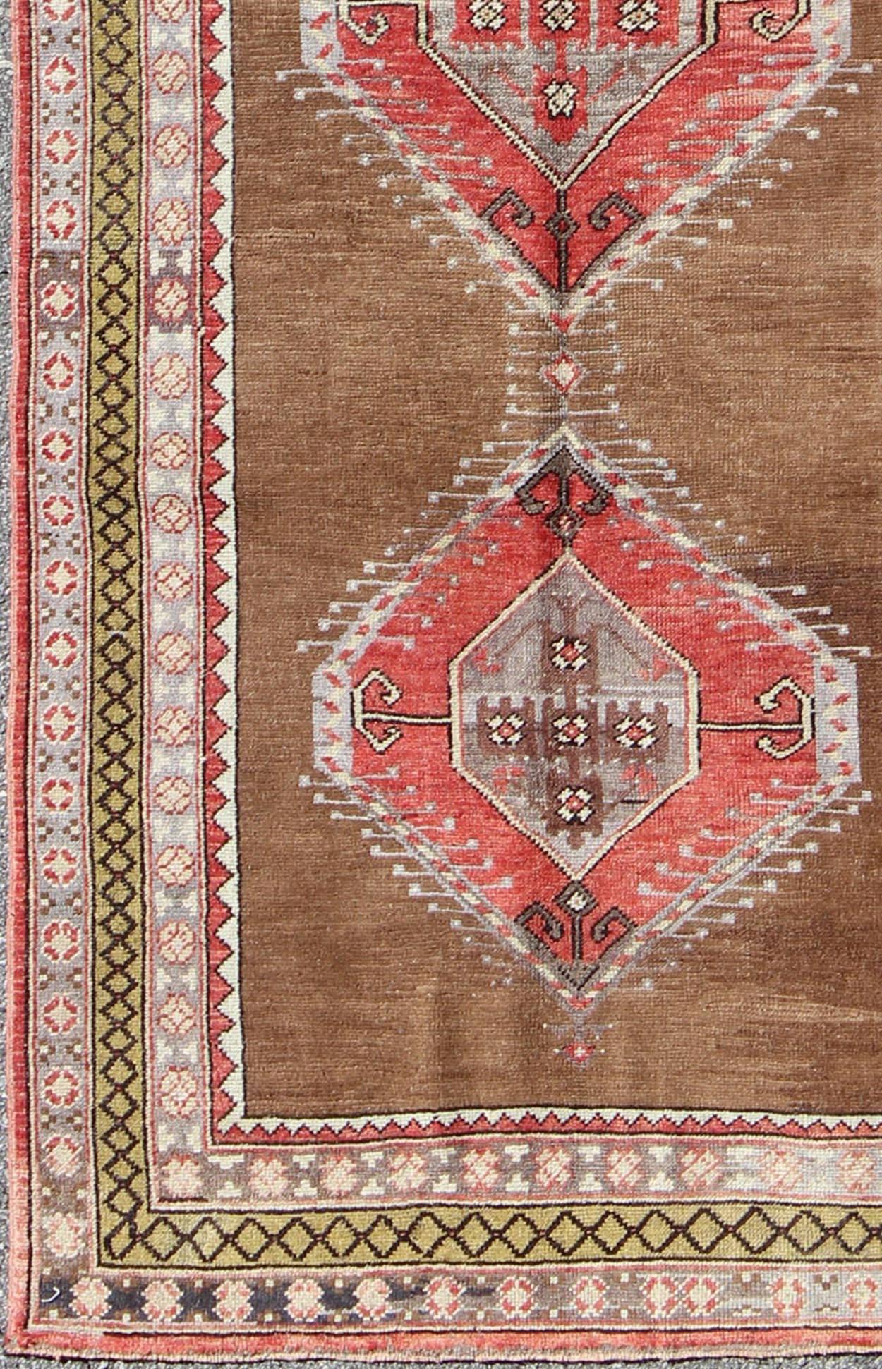 This beautiful vintage Oushak runner from mid-20th century Turkey features a Classic Oushak design, which is enhanced by its lustrous wool. The faint brown ground is home to three large and elegant medallions of red, brown, gray, charcoal and ivory