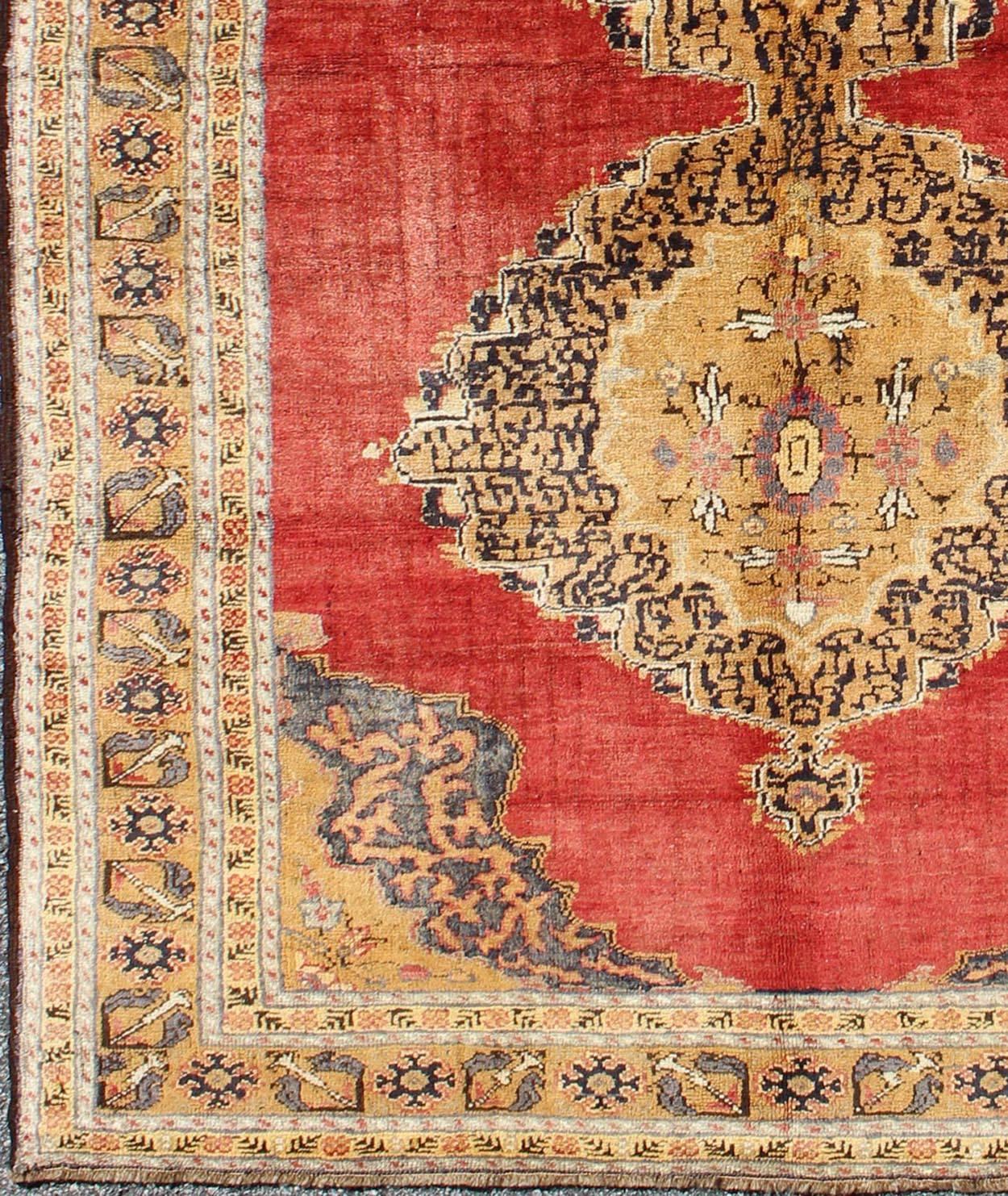 Made is the late Ottoman era, this stunning Turkish rug displays a red background with two medallions in the center. The medallions are in gold with black scroll works while the four corners and borders are in gold with gray and black highlights.