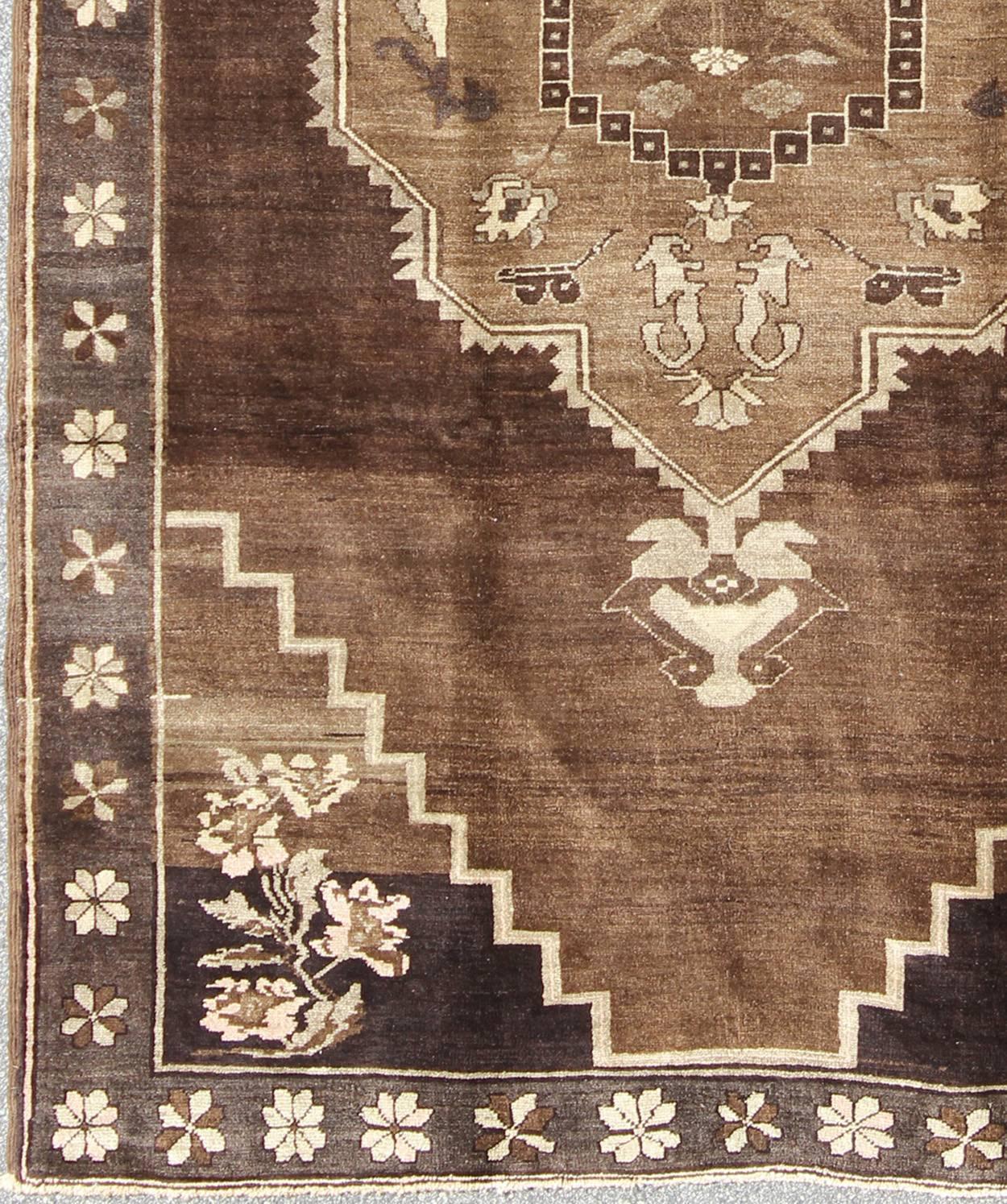 Vintage Brown Turkish Rug with Geometric Design in Various Brown Colors.
Set on a variation of light and dark brown and gray colors, the pale taupe and light blue colored roses are accented by light green leafs and vine designs. The border continues
