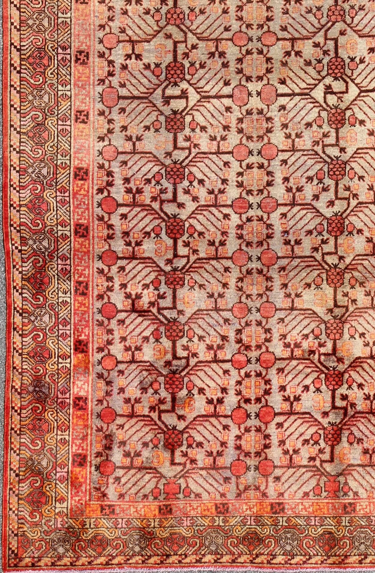 Großer antiker Khotan-Teppich mit Granatapfelmuster in Taupe, Grün, Rot und Braun.
Dieser attraktive antike Khotan-Teppich ist ein spektakuläres Zeugnis für die Komplexität des turkestanischen Designs. Der neutrale Farbton des zentralen Feldes