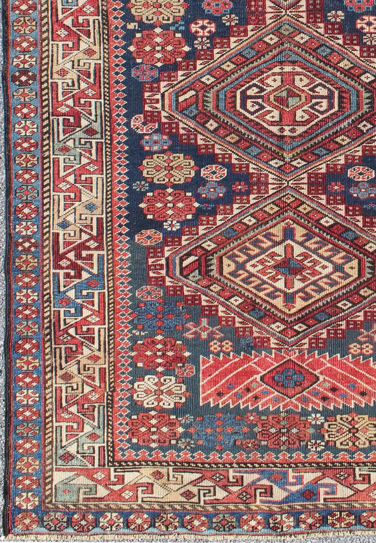 This antique, late 19th century Kazak rug from Russia displays three bold, geometric central medallions set on an indigo background and surrounded by multiple complementary geometric borders.

Measures: 4'4 x 7'7.

Antique Kazak Rug with