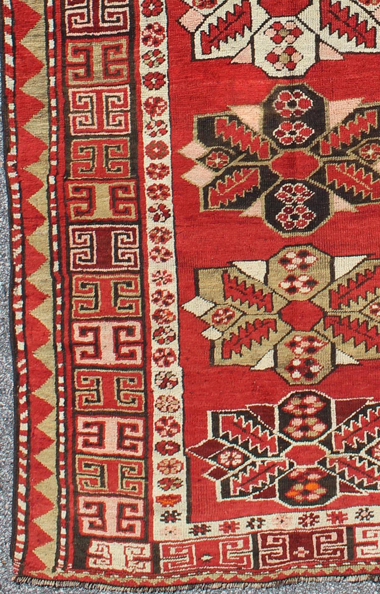Red background antique Kazak runner with medallions and tribal design, Keivan Woven Arts / rug g-1204, country of origin / type: Caucasus / Kazak, circa 1900

The field design of this antique Kazak runner features medallions of differing colors