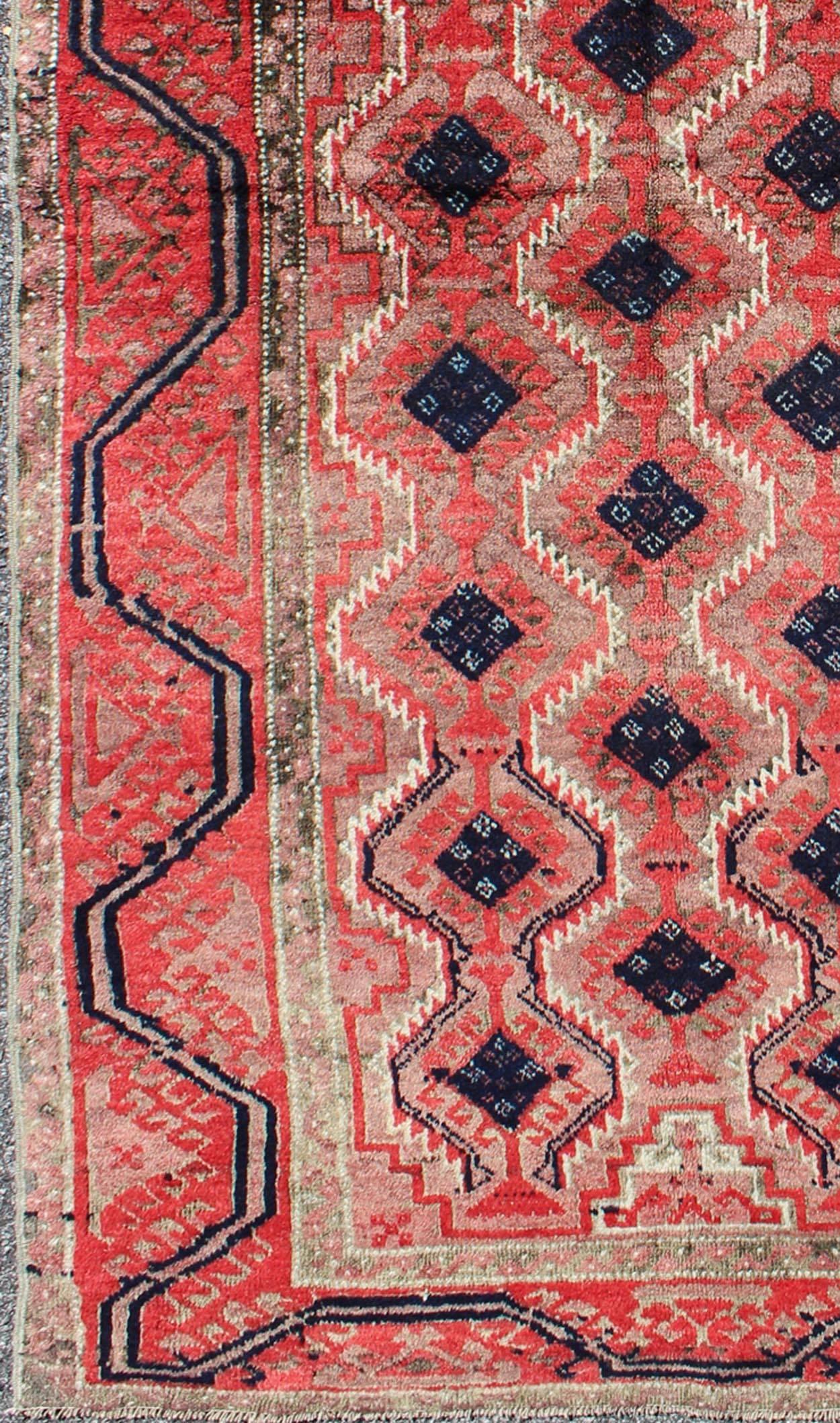 This impressive and complex vintage Afghan Beluch rug (circa mid-20th century) features an all-over diamond-shaped pattern flanked by geometric motifs in the borders. Colors include various shades of red, taupe, ivory, gray, and charcoal.

Measures: