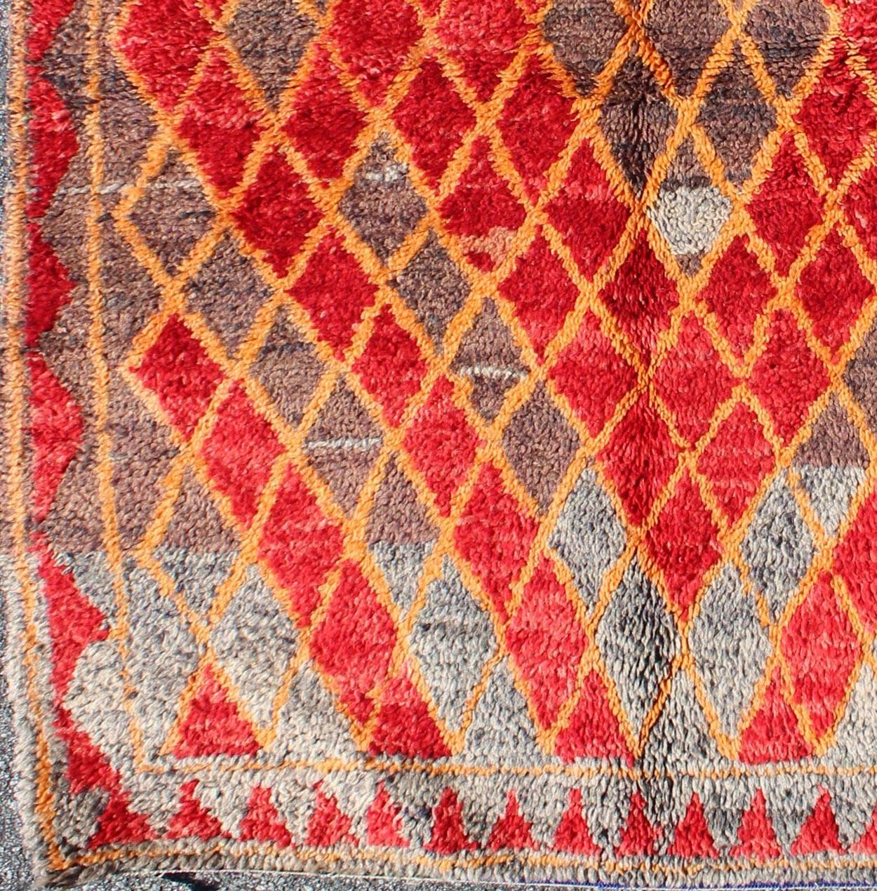 Marokkanischer Teppich aus der Mitte des Jahrhunderts mit orangefarbenen, roten, braunen Diamanten und blauen Fransen. Keivan Woven Arts /  teppich sk-628, herkunftsland / typ: Marokko / Tribal, etwa Mitte des 20. Jahrhunderts

Dieser wunderbare