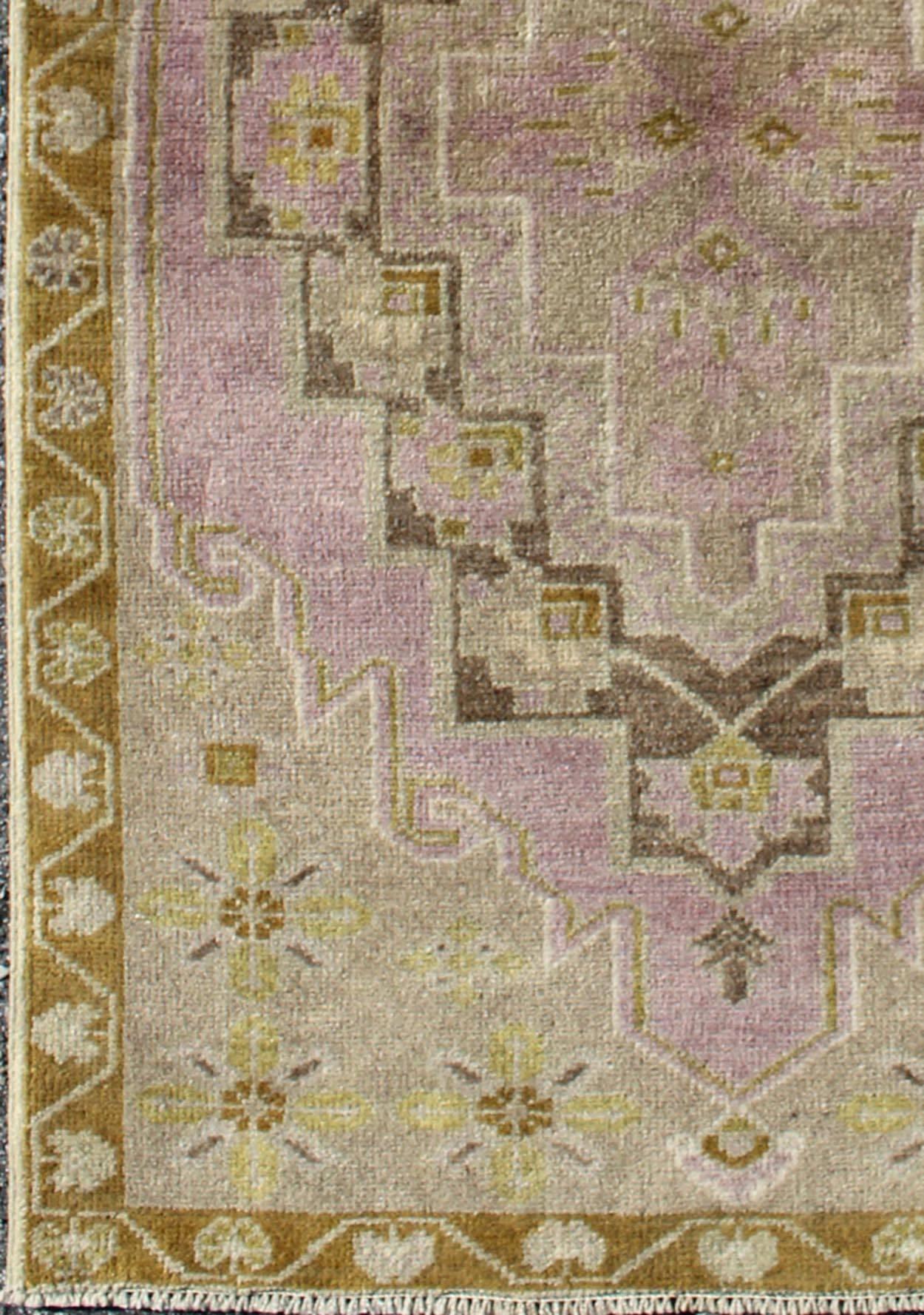 This vintage Turkish oushak rug features a unique blend of colors and an intricately beautiful design. The multi-layered central medallion is complemented by a symmetrical set of floral motifs in the surrounding field and border. The various shades