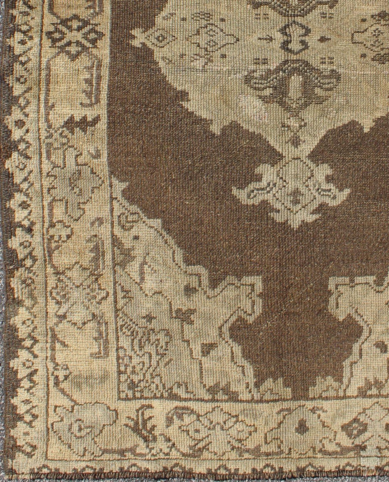 Chocolate background vintage Turkish Oushak rug with floral medallion in cream, rug moz-09, country of origin / type: Turkey / Oushak, circa mid-20th century.

This vintage Turkish Oushak carpet (circa mid-20th century) features a central
