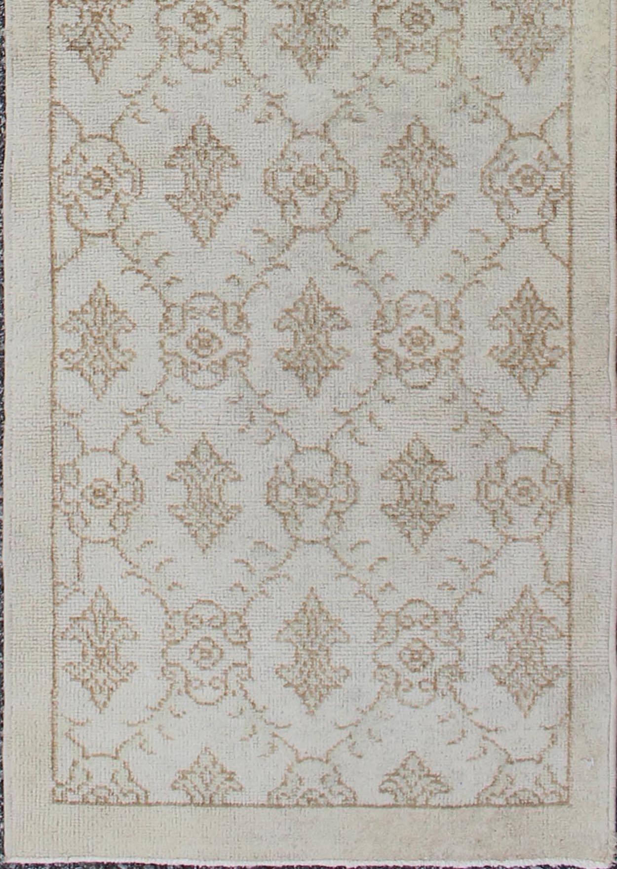This vintage Turkish Oushak runner (circa mid-20th century) features an all-over latticework design with arrowhead figures throughout. The rug's qualities are enhanced by its particularly soft and lustrous wool. Colors include ivory and light