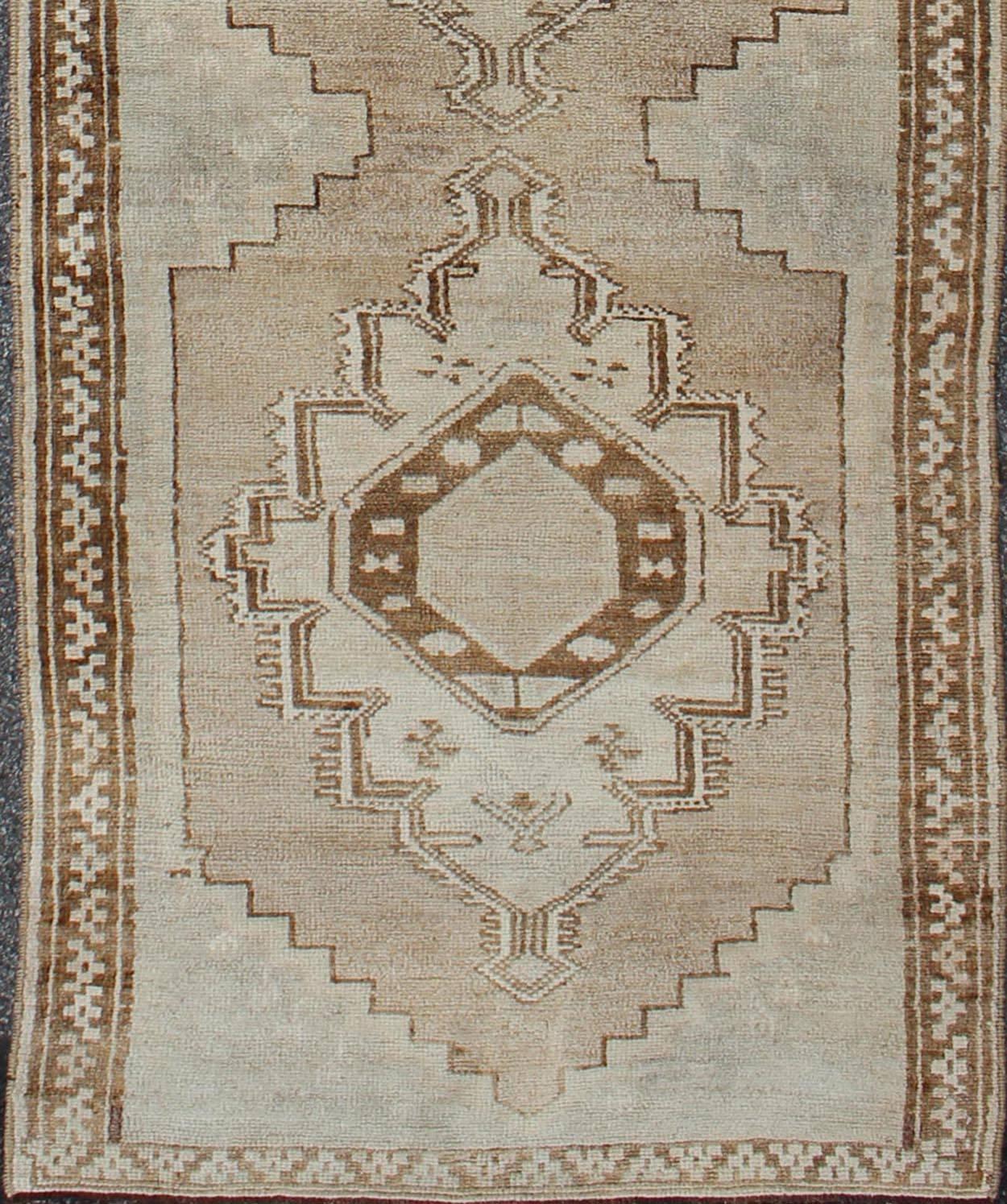 Measures: 2'10 x 10'5.

This vintage Turkish Oushak gallery rug (circa mid-20th century) features a unique blend of colors and an intricately beautiful design. The central medallions consist of a vertical line of geometric and tribal elements,
