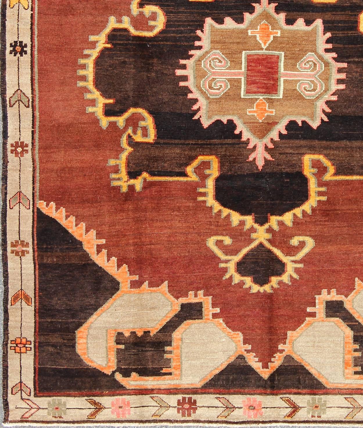 Bold Design Vintage Turkish Rug in Sienna, Brown, Back, Cream and Yellow.
This unexpected bold Turkish carpet is composed of a reddish-brown background with dark charcoal and brown corners and a medallion. The brilliant orange and yellow highlights