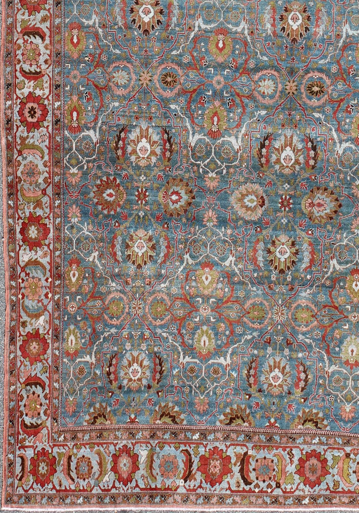 Superbe tapis persan ancien de type Malayer à fond bleu  et des fleurs colorées subgéométriques. Ce tapis présente une variation de couleurs bleues dans le fond et une bordure bleu ciel. La gamme de couleurs comprend le vert acide, le rouge doux, le