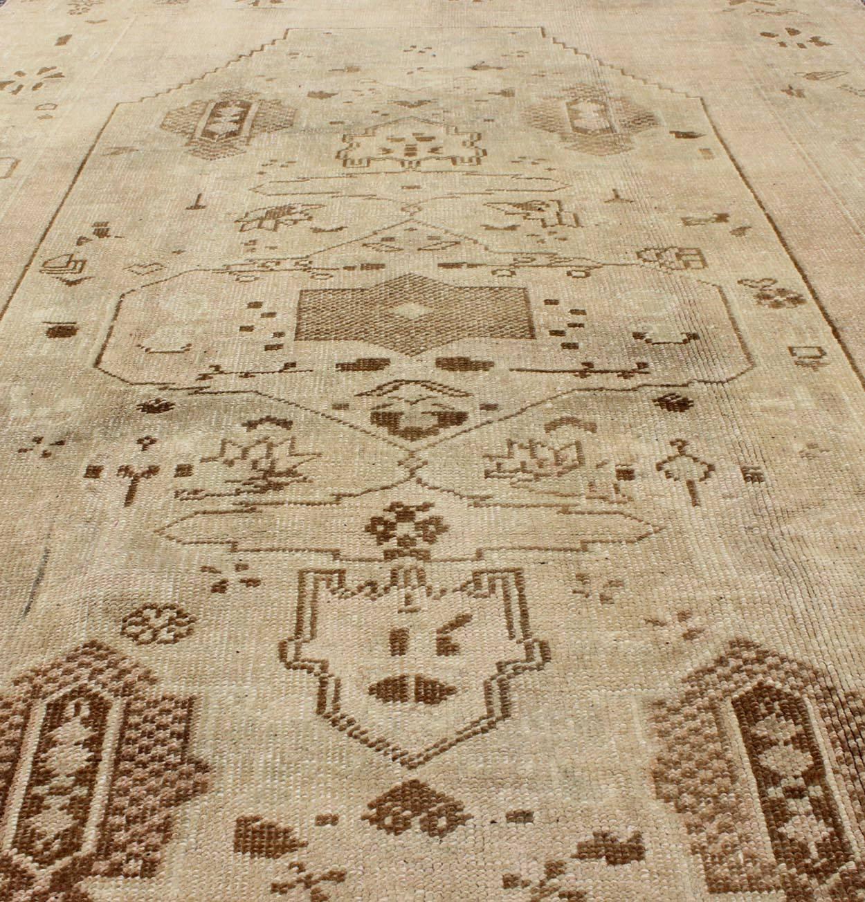 Wool Vintage Turkish Oushak Rug with Tribal Motifs in Shades of Brown and Cream For Sale