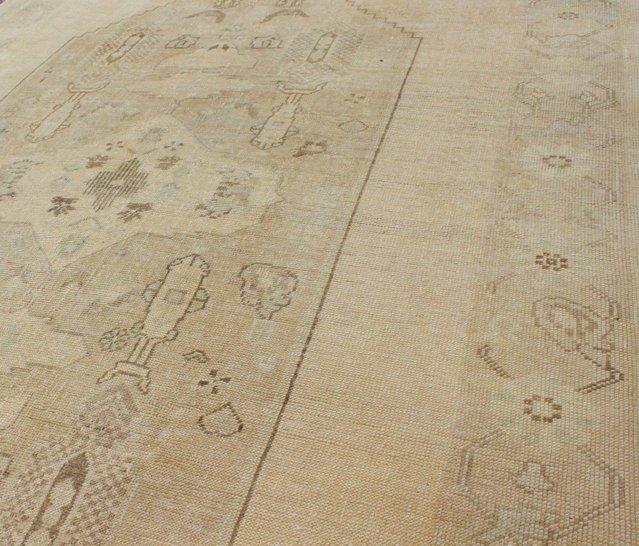 Mid-20th Century Faded Turkish Oushak Rug with Central Medallion Design in Cream and Brown For Sale