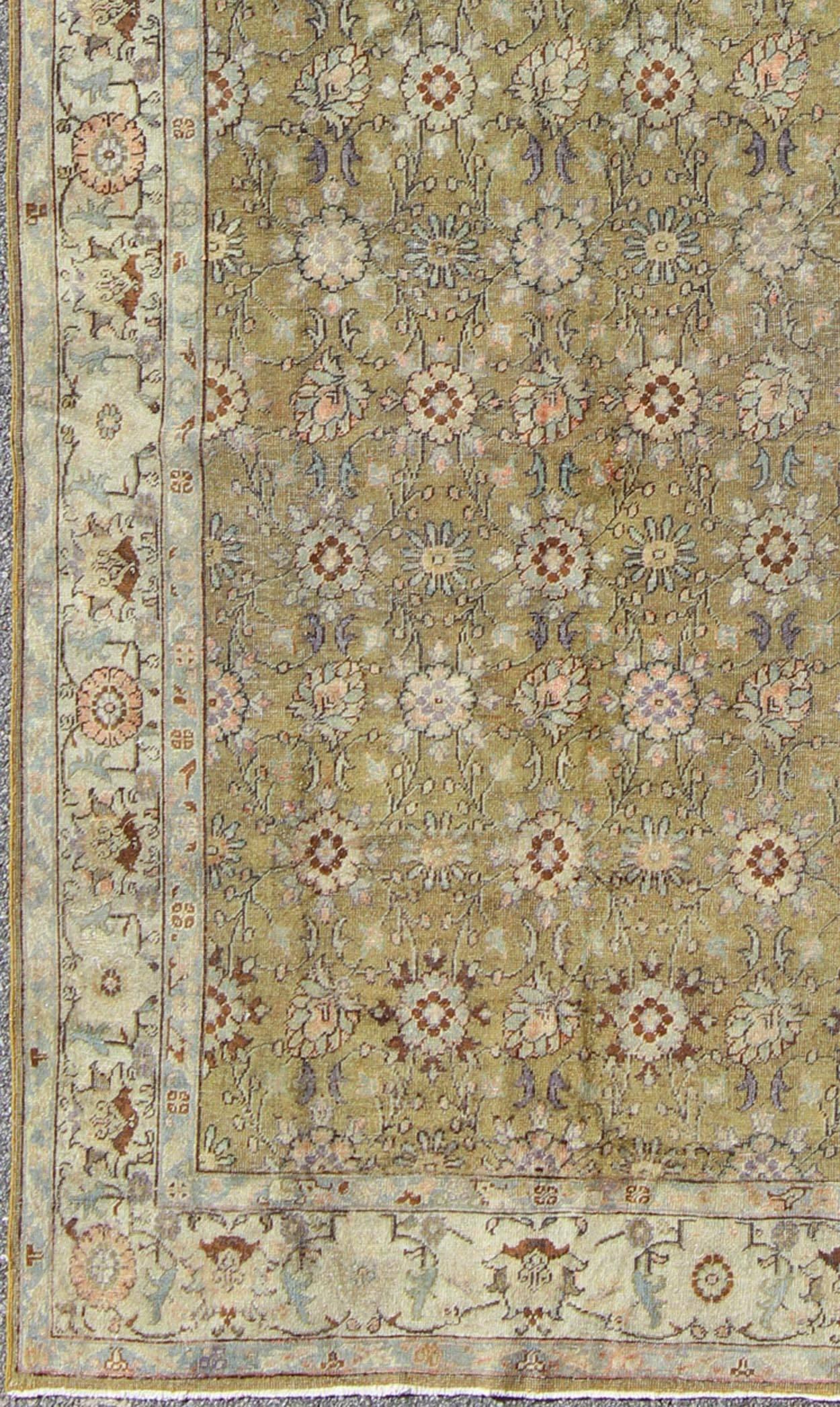 This broad antique Turkish oushak runner is remarkably elegant in both color and design. The central field of green plays host to a variety interconnected blossoms in an all-over pattern with intermixed palmette motifs. The simplified inner and