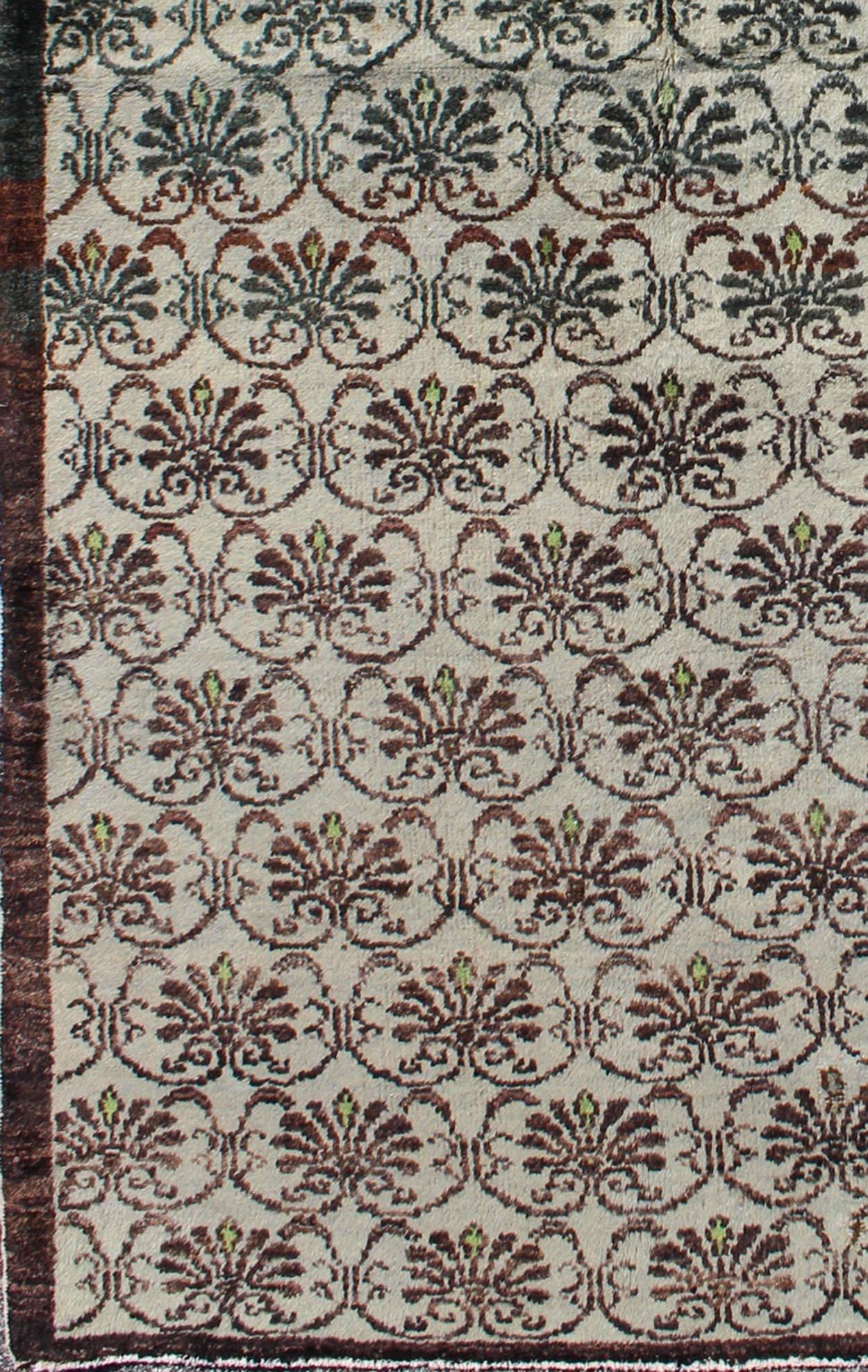 Dieser Oushak-Teppich (ca. Mitte des 20. Jahrhunderts) zeigt ein Allover-Muster aus miteinander verbundenen, vertikal angeordneten Rankenblüten. Die Farben sind schokoladenbraun mit einem Hauch von Grün auf einem elfenbeinfarbenen