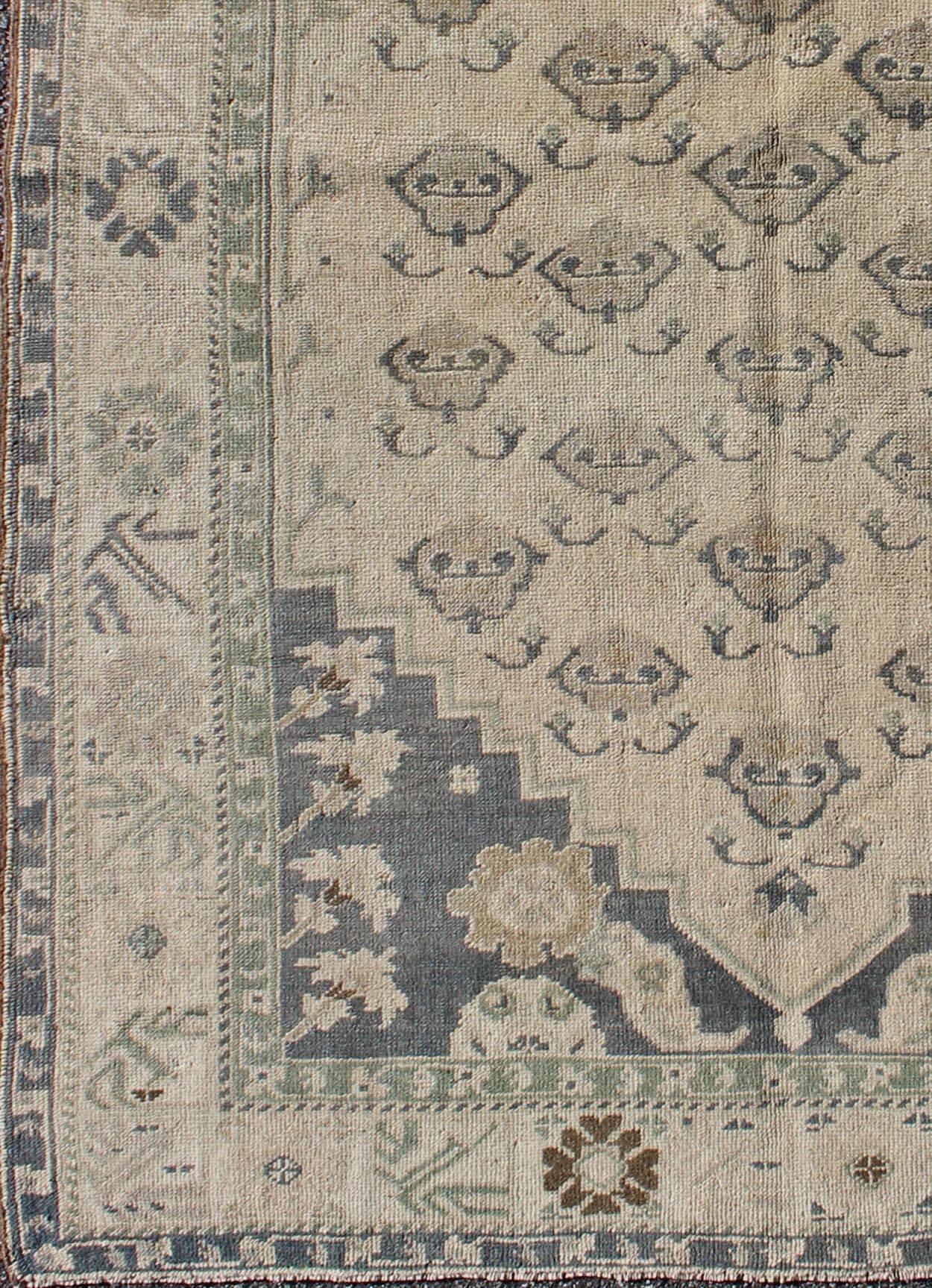 All-over blossom design vintage Turkish Oushak rug in taupe and greyish blue, rug tu-TRS-3613, country of origin type: Turkey Oushak, circa 1940.

This Oushak carpet (circa mid-20th century) features an all-over pattern of vining blossoms spread
