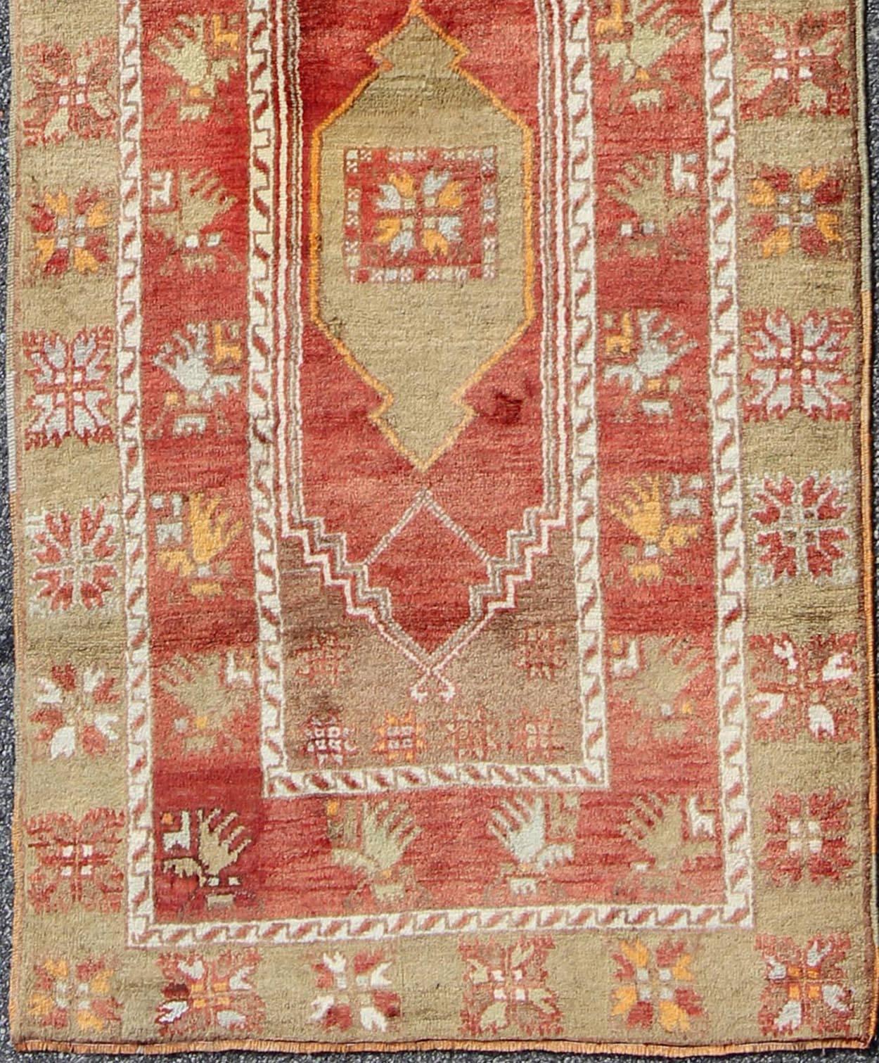 This beautiful vintage Oushak runner from 1940s Turkey features a classic Oushak design, which is enhanced by its lustrous wool. The dark red ground is home to two vertical medallions and various other tribal motifs. Colors include red, pale green,
