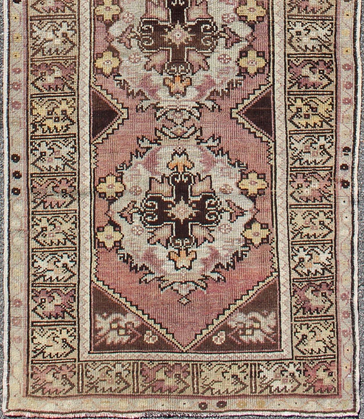 Measures: 2'11'' x 9'8''.
This beautiful vintage Oushak runner from 1940s Turkey features a Classic Oushak design. The reddish-colored ground is home to interconnected, layered, floral, vertical medallions. Colors include chocolate brown, light