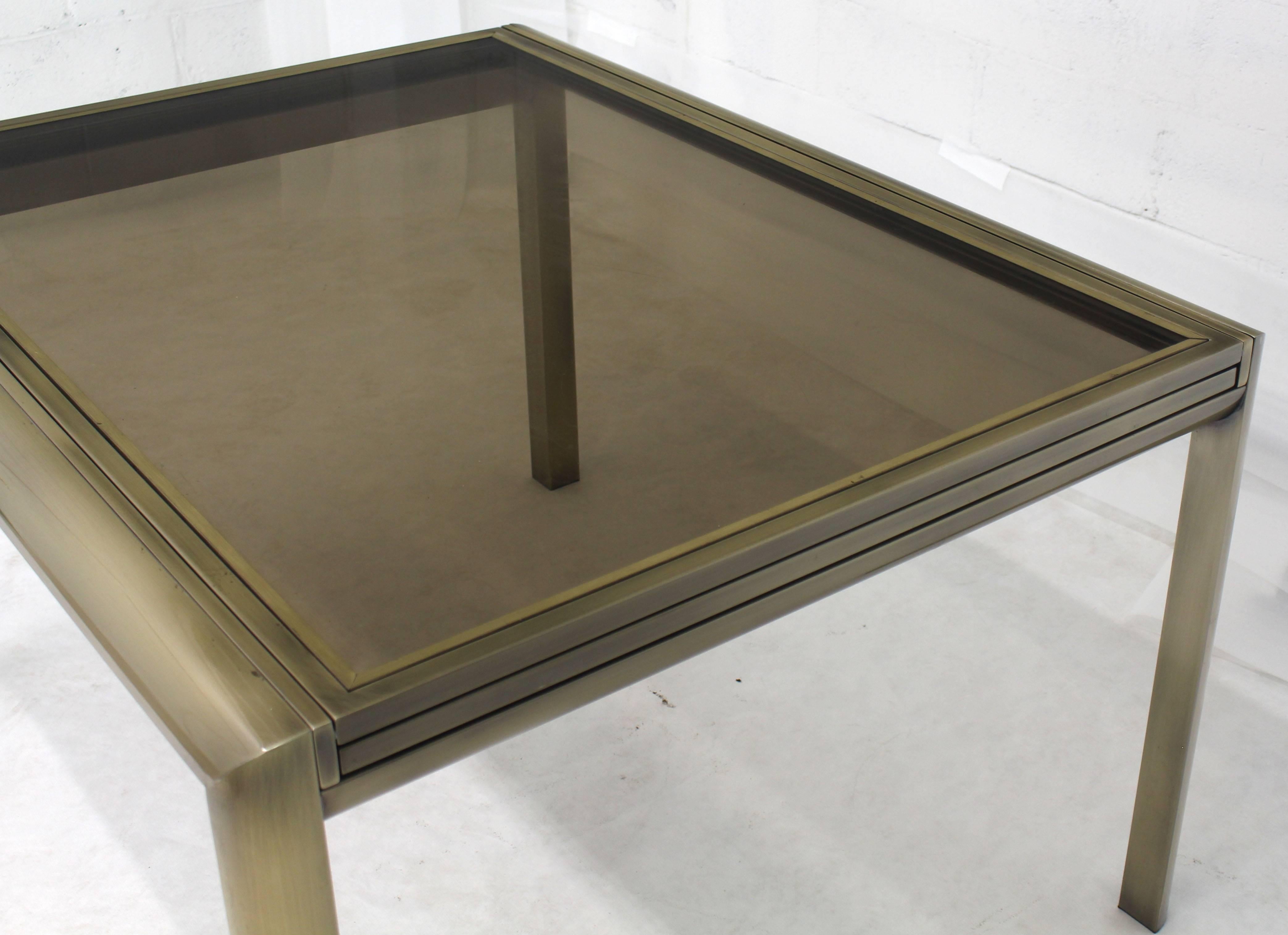 Mid-Century Modern expandable dining table in brass and bronze glass. Beautiful original condition.
 