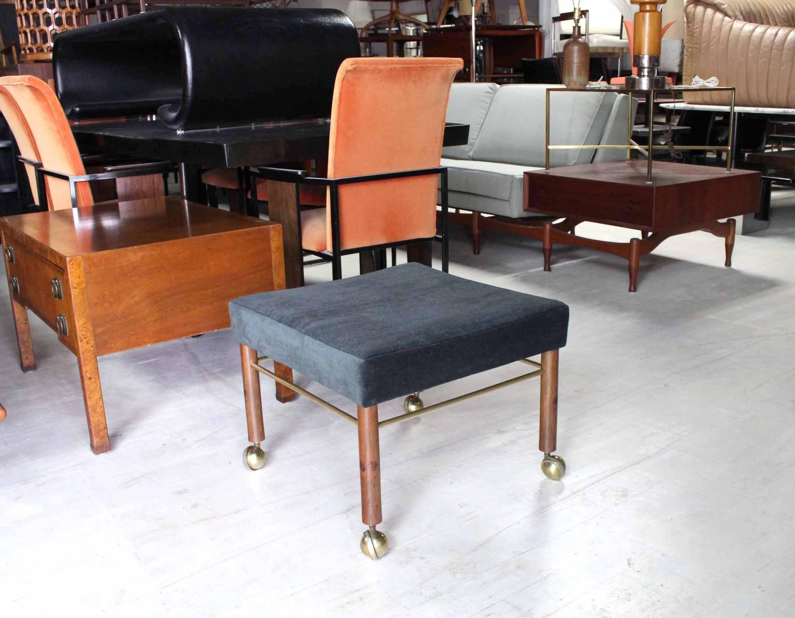 Square upholstered bench stool on walnut dowel legs with brass stretchers.