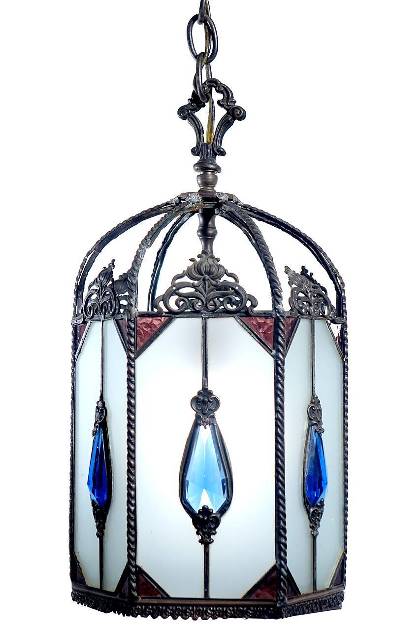 This is a nice clean six-sided foyer lamp. It is mostly milk glass with lavender stained glass accents and an aqua teardrop cut glass jewel. The glass bottom is hinged to change the bulb.