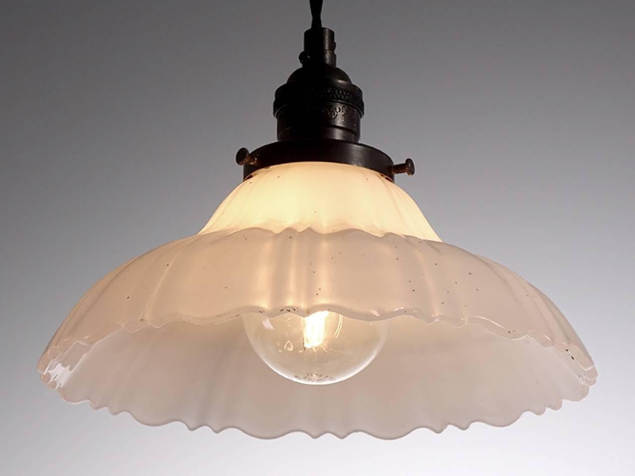 Softly curved bell shaped pendants are a classic. They feel at home with any style decor. This example is an extra heavy thick-thin pattern in cast Clam Broth glass with a scalloped edge. The pattern has two thin ribs and one wide. The lamps are