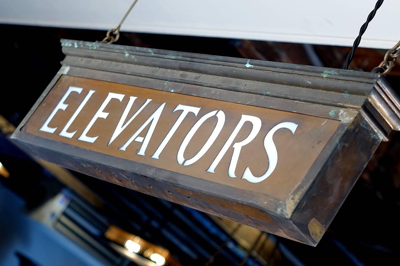 This is an early two bulb elevators sign. It has beed rewired, working and is all original. The frame is bronze with brass cut-out letters over milk glass.