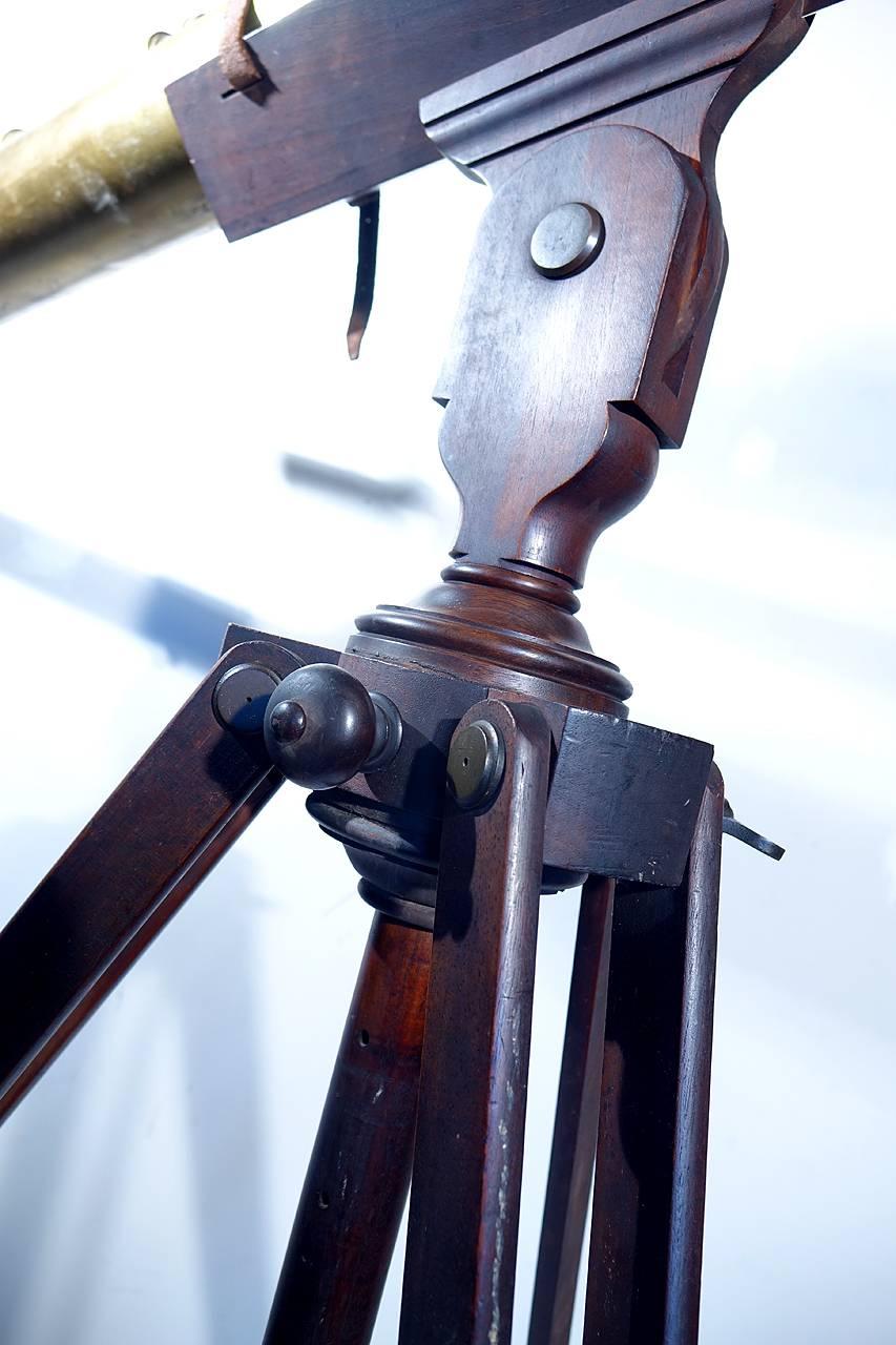 This large early brass telescope. It's quite an impressive show piece. The brass scope is 72 inches long with a 4 inch diameter. The mahogany tripod the correct belted cradle type for this scope and the wood finish is original. There is nice aged
