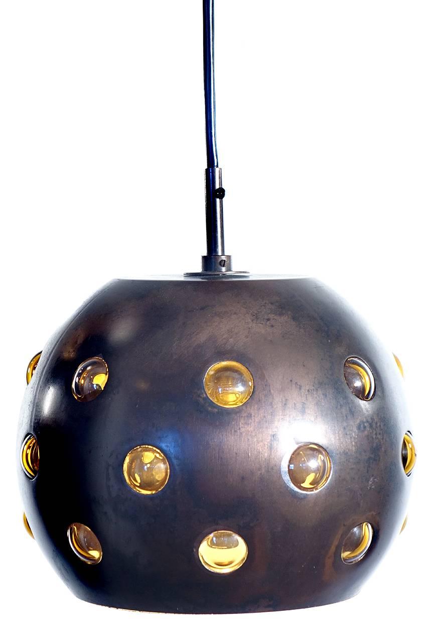These unique pendants are Mid-Century classics by one of the important modern finnish designers. Nanny Still designed for RAAK in the 1950s-early 1960s. These lamps are perforated 8 inch diameter copper spheres lined with amber handblown glass.