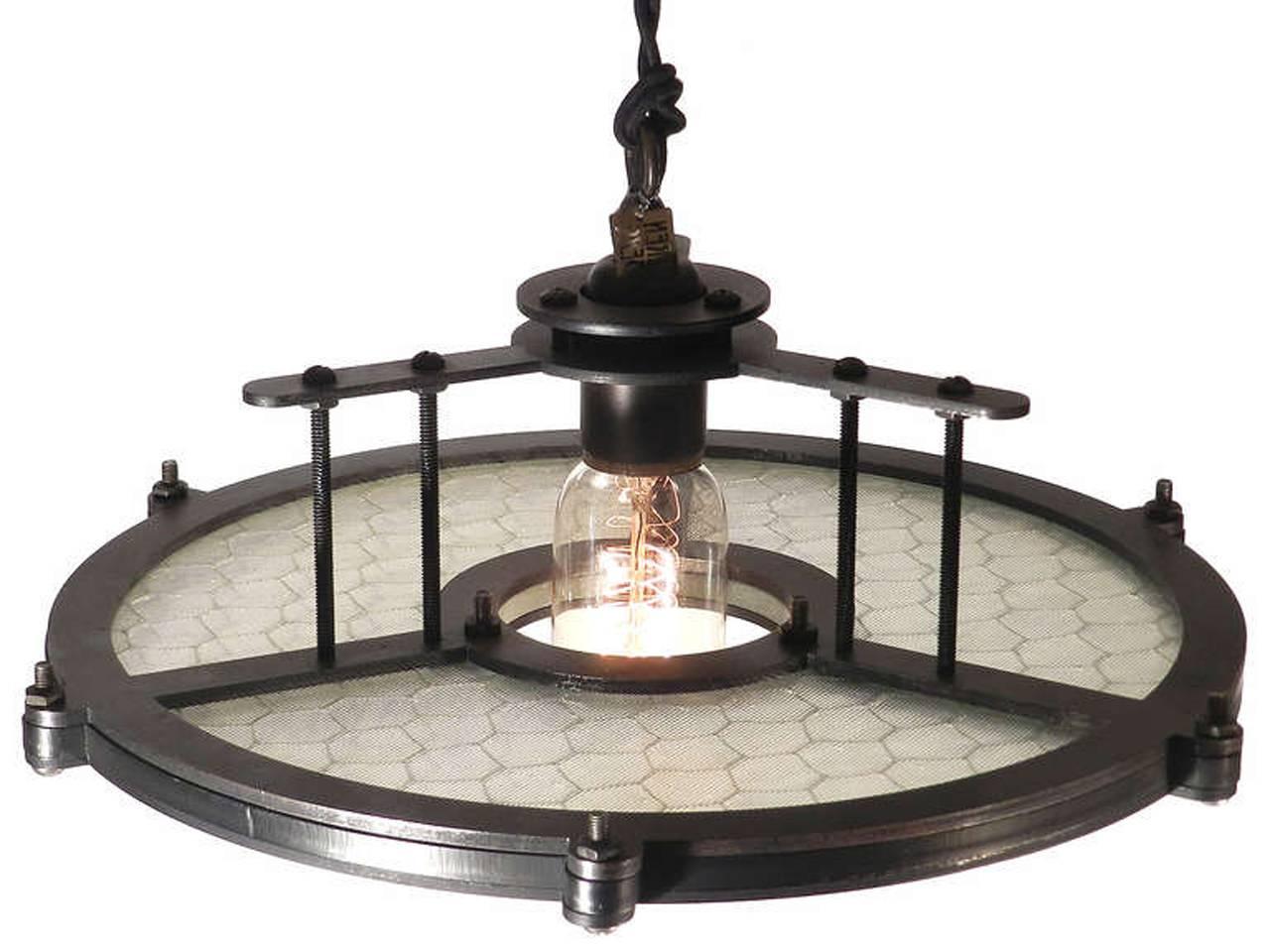 These unique 13 inch diameter pendants feature 80 year old reeded Industrial wire glass. We designed the simple iron frame to highlight the beauty of this antique utilitarian factory glass. The iron frame has an aged black finish. The socket is