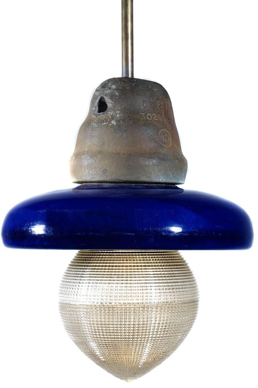 These pendants started high voltage electrical insulators. They are heavy and solid ceramic with a striking baked on cobalt blue finish and an iron crown.
This has been fitted with a dental acorn Holophane shade. The pipe drop can be set to your