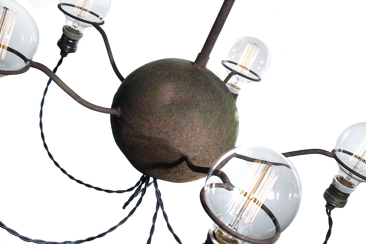 This is a very unique five-light chandelier. It has an ancient deeply pitted 8 inch hollow ball at the center. You can't duplicate a patina like this. We're guessing it's was originally used as an Industrial float of some type. There are five